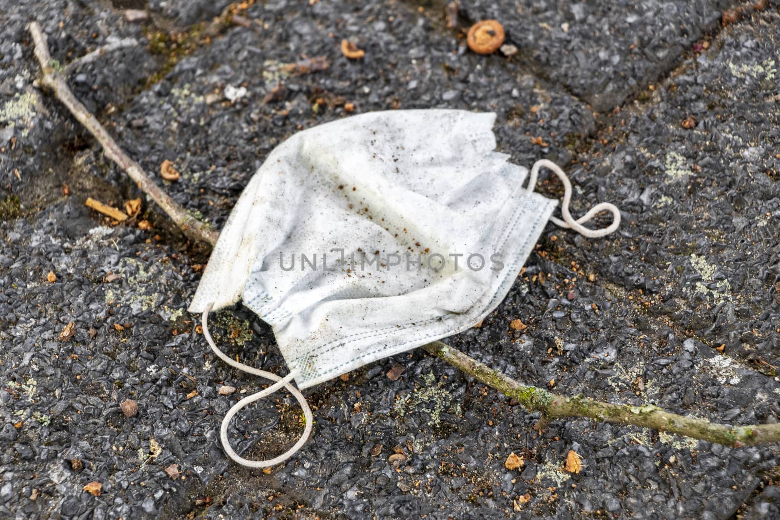 Surgical white masks on the ground. Corona virus pollution. by Arkadij