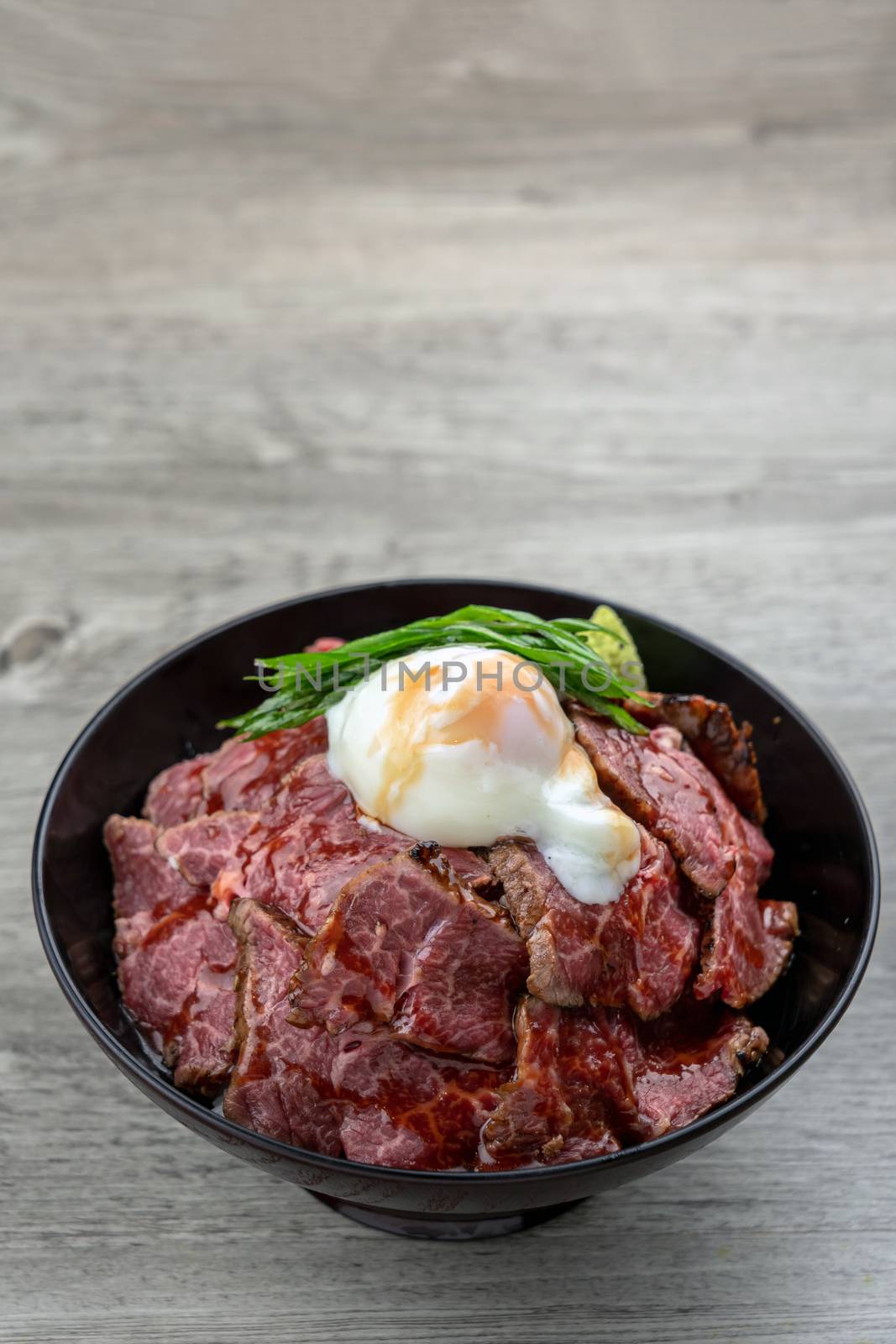 Gyudon raw beef and stream egg serve with rice in blow over the wooden table, Luxury Japanese food concept