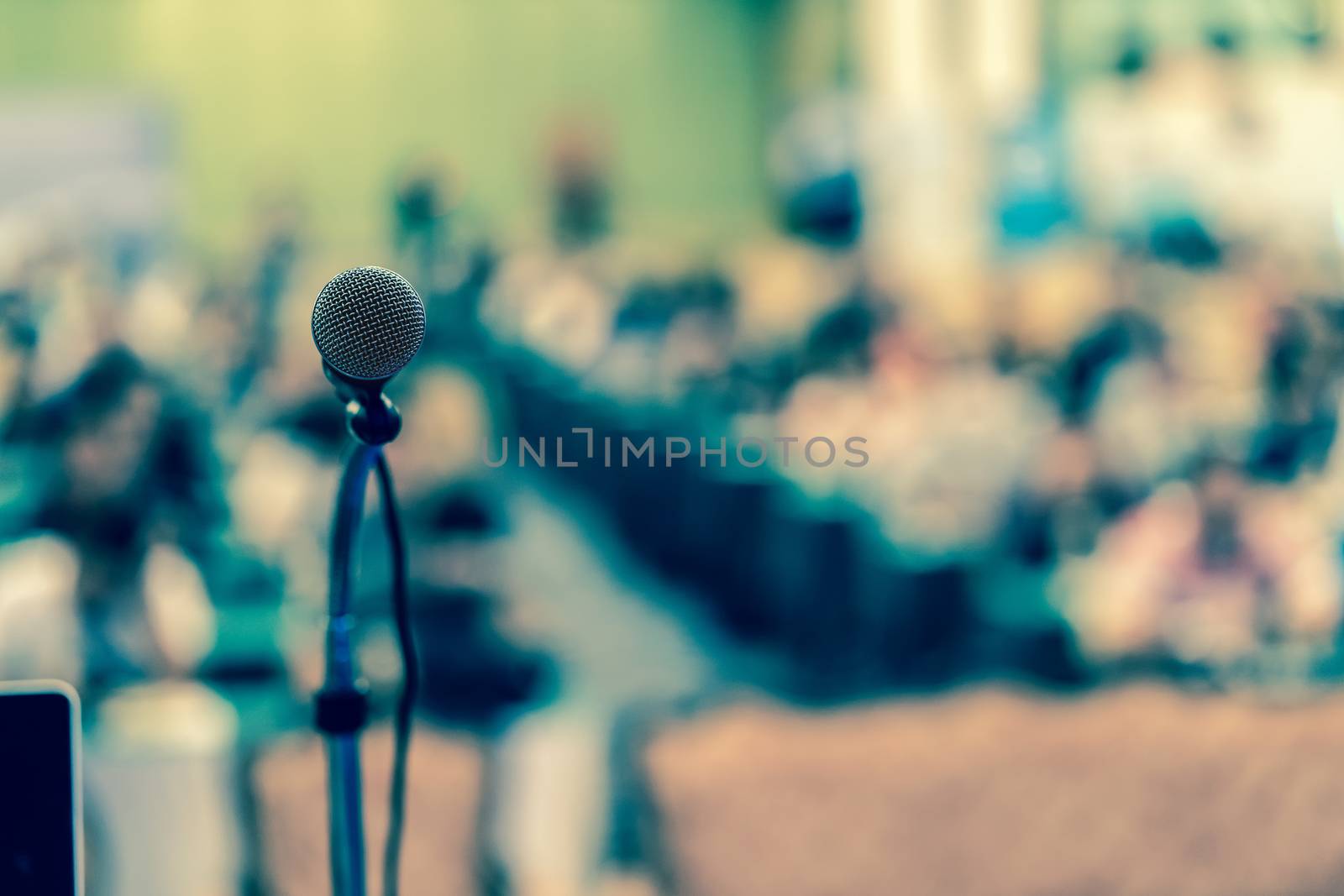 Microphone over the Abstract blurred photo of conference hall or seminar room with audience background, education and learning concept