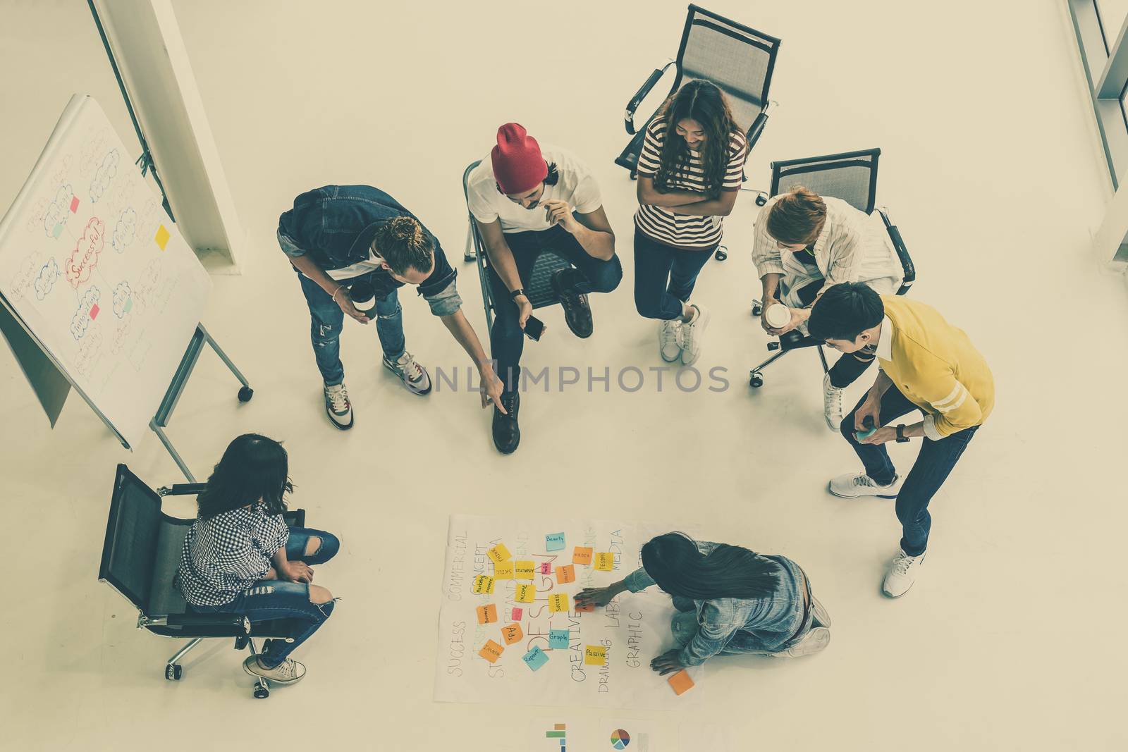 Top view Group Of Asian and diverse Business people with casual suit brainstorming and helping to put postit paper on the project chart together in the modern workplace, multiethnic teamwork concept