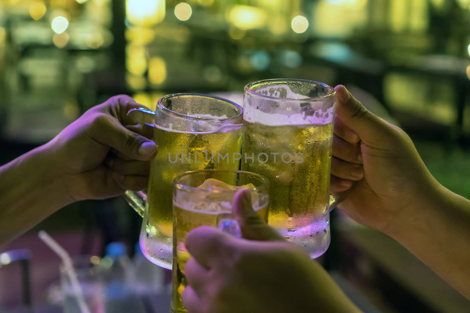 Three Glasses of Beer cheers together between friend in the low light bar and restaurant. relax and drink concept