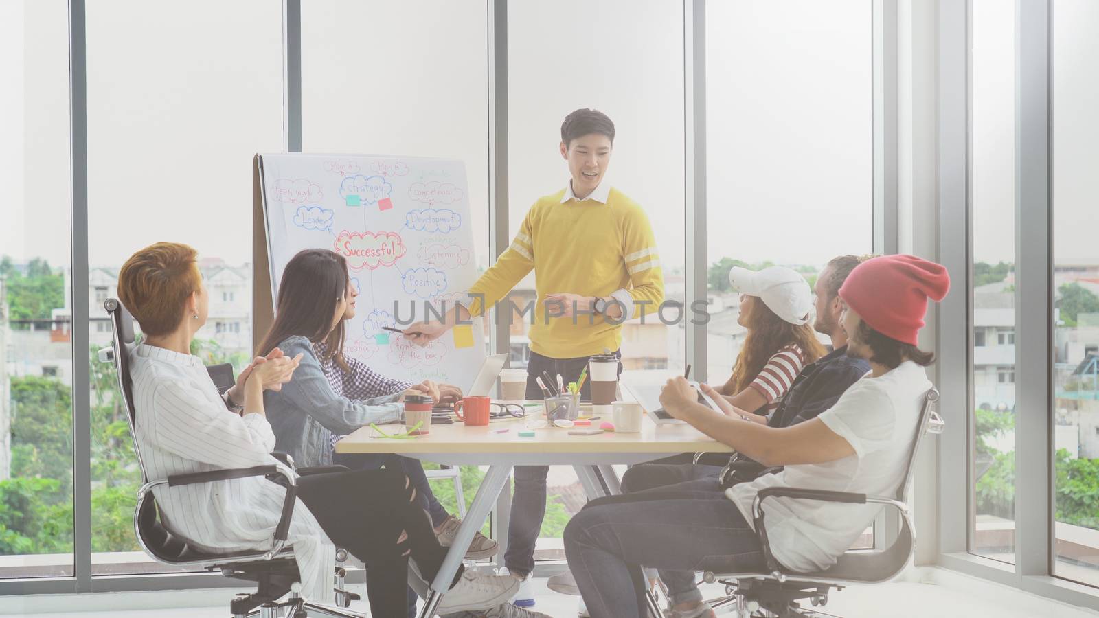 Asian young manager presenting the creative ideas in front of Group Of Asian and Multiethnic Business people with casual suit in happy action in the modern workplace