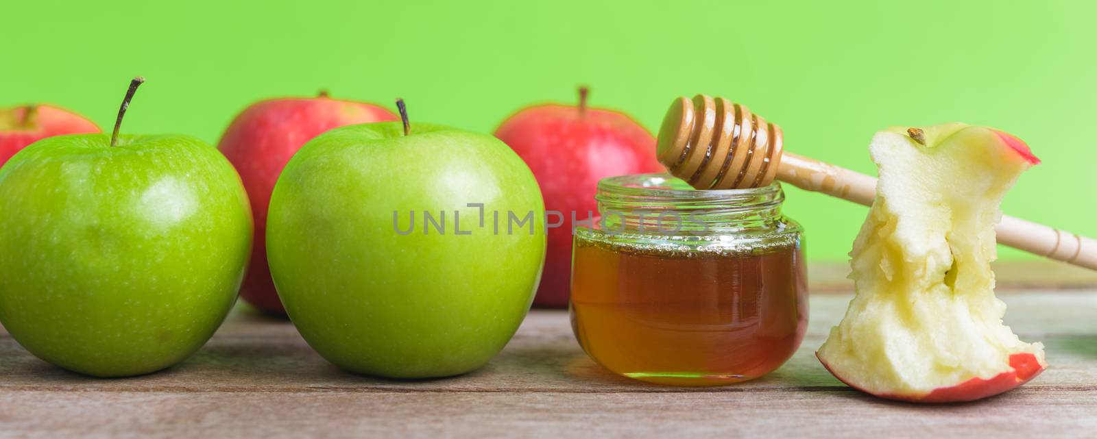 Jewish holiday, Apple Rosh Hashanah dessert, on the photo have honey in jar have red apples and green apples on wooden with green background