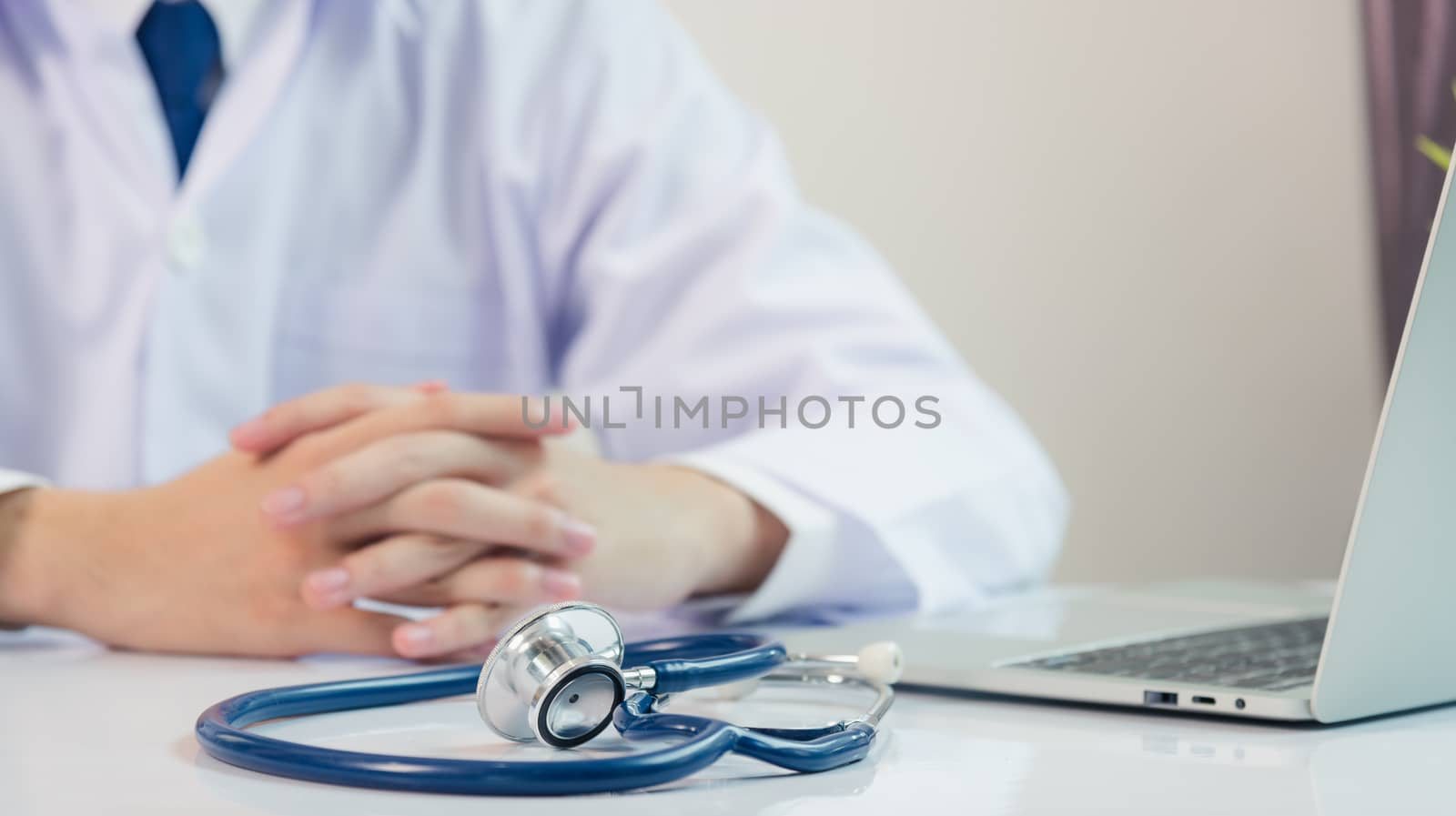 Medicine doctor's working on desk. Closeup of Stethoscope. Physician man video call sit hand in hand and listen patient explain on front laptop computer at hospital office, Healthcare medic concept