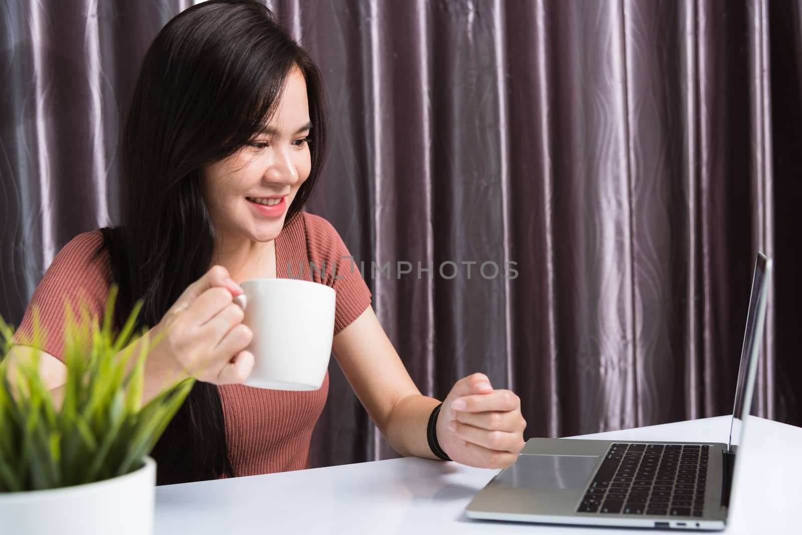 Work from home, Smiling Happy Asian business young beautiful woman sitting on desk workspace video call conferencing with team by webcam laptop computer technology at home office