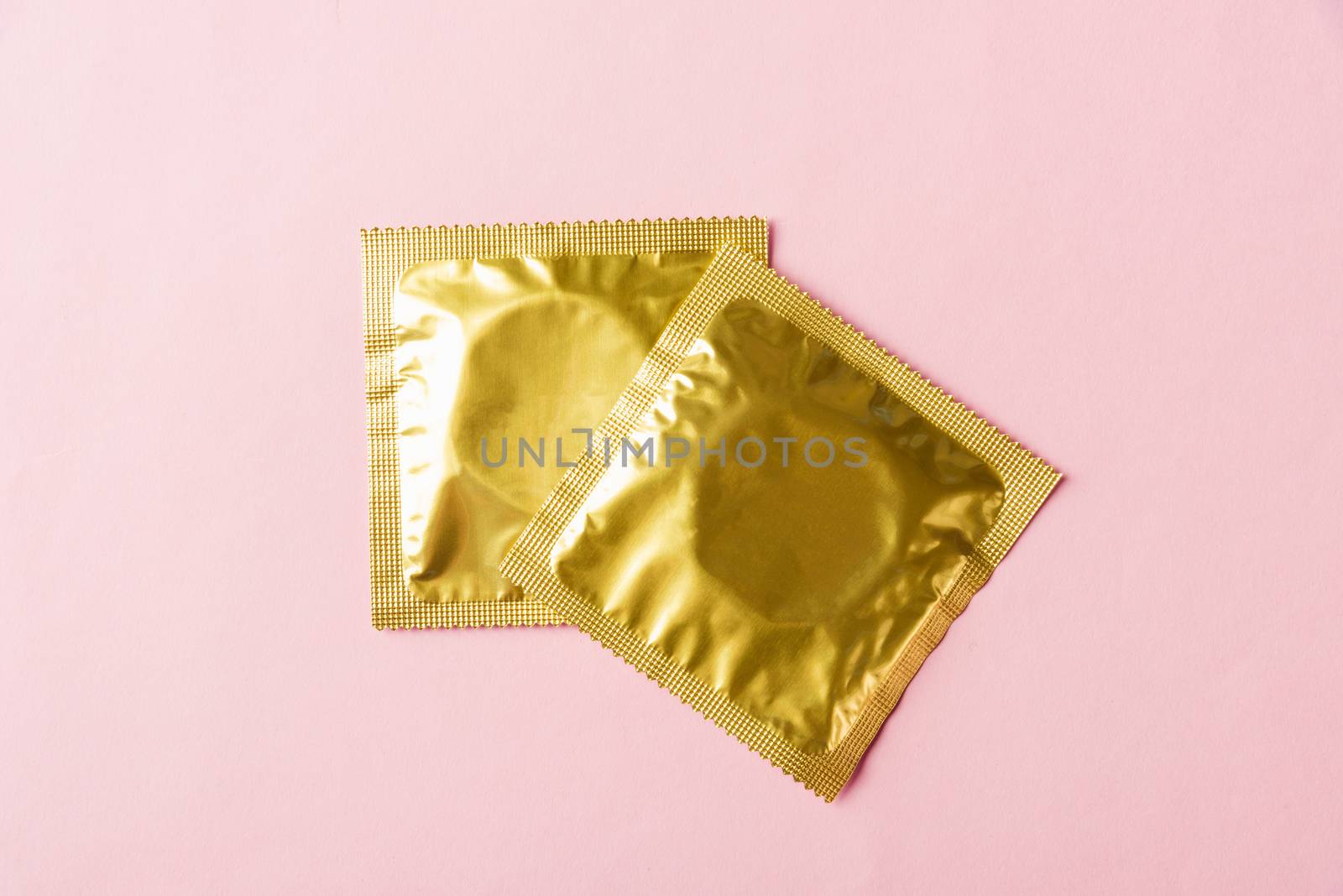 World sexual health or Aids day, Top view flat lay condom in wrapper pack, studio shot isolated on a pink background, Safe sex and reproductive health concept