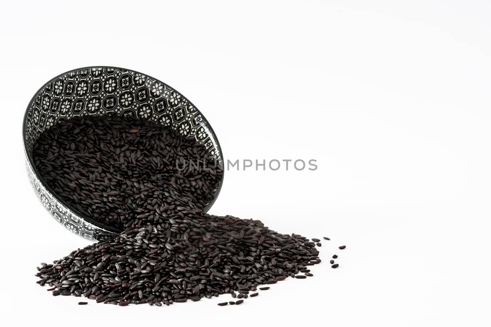 Raw black rice in a bowl isolated on white background