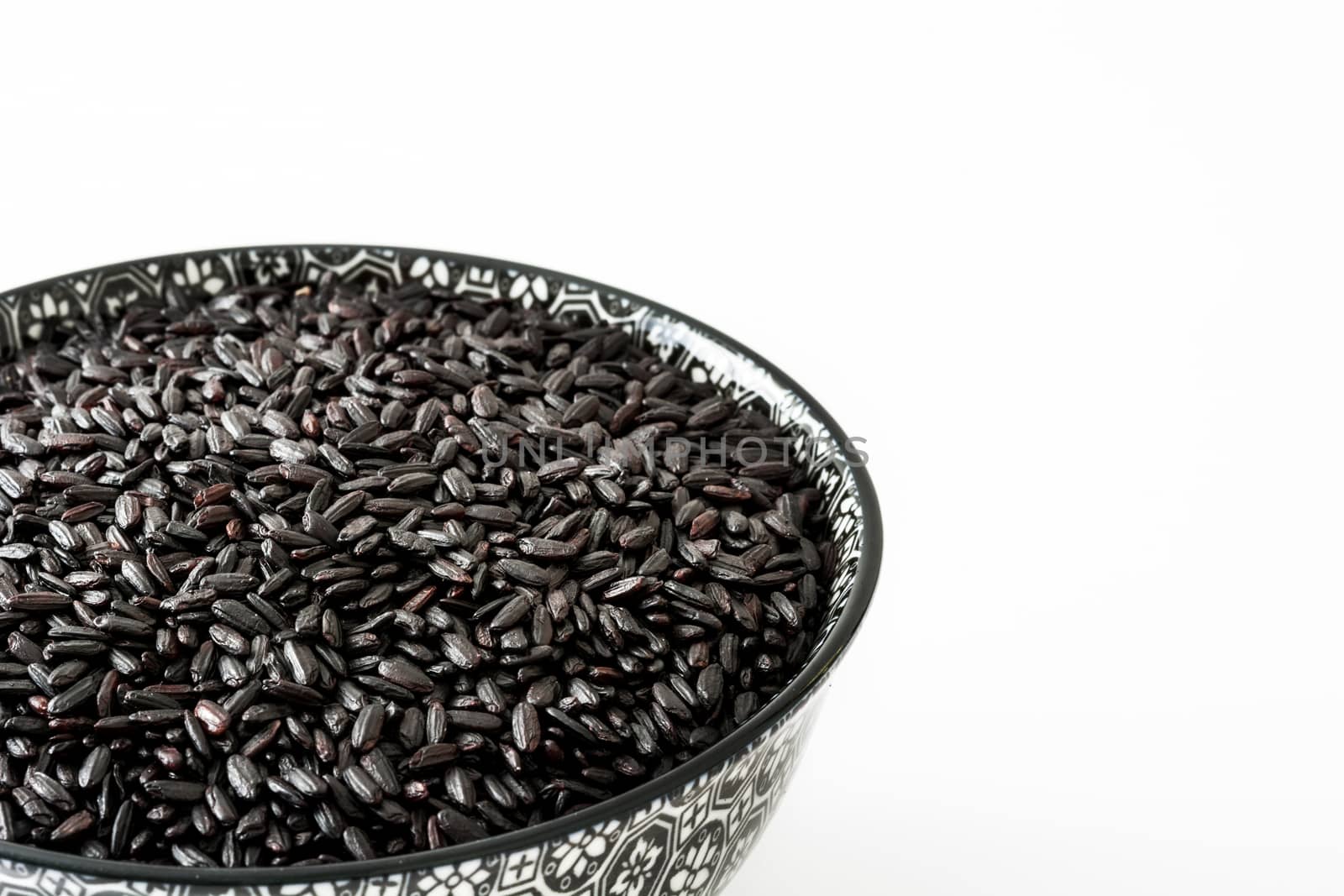 Raw black rice in a bowl isolated on white background