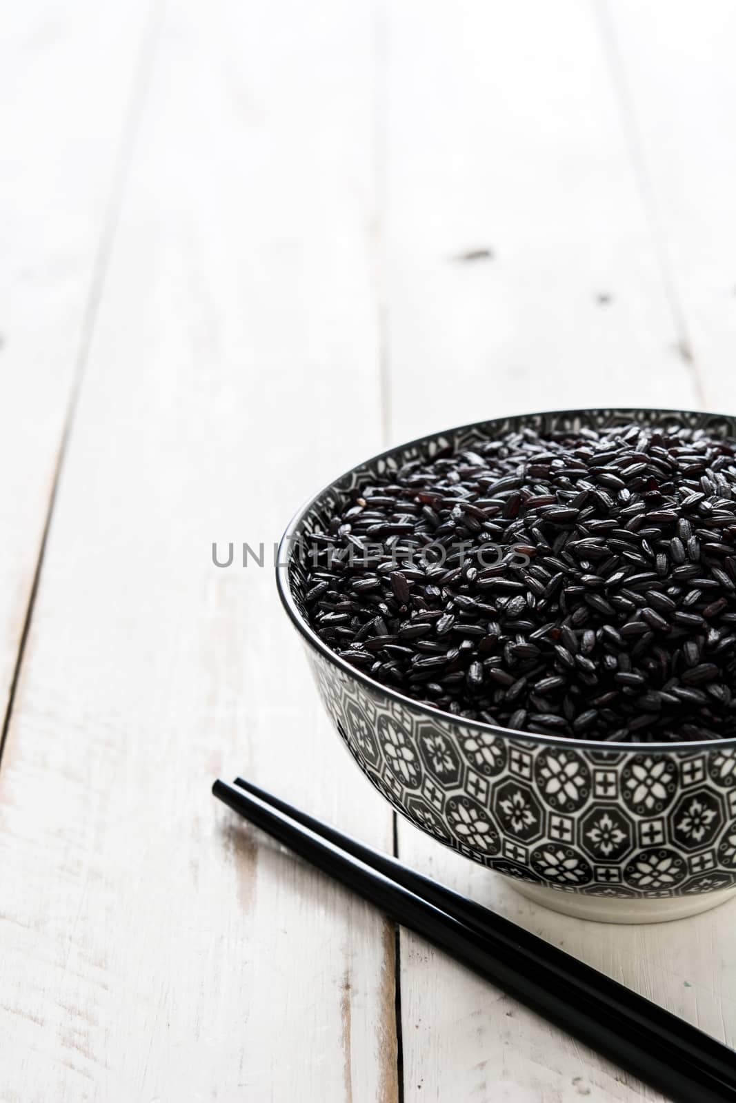 Raw black rice on white wooden background by chandlervid85