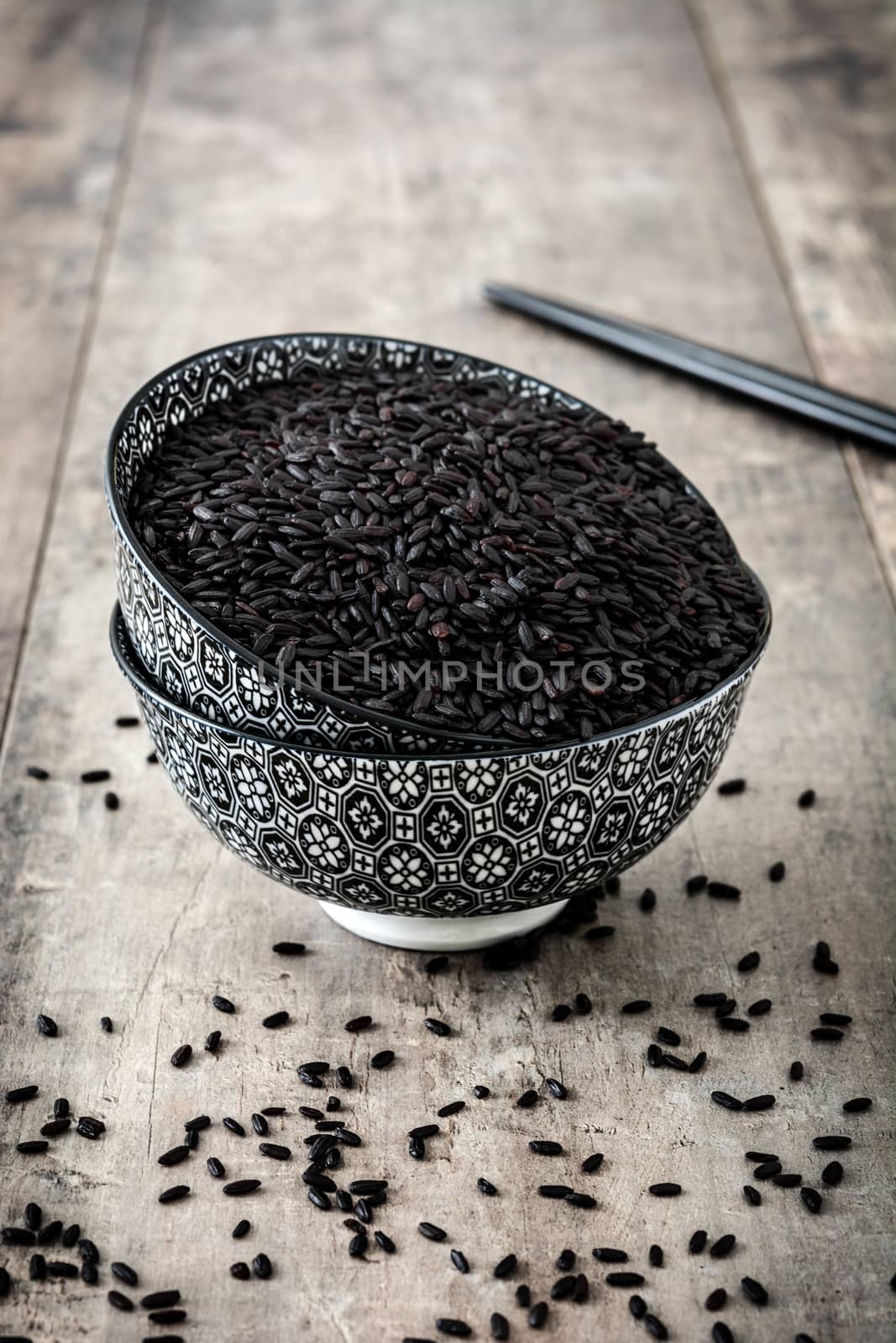 Raw black rice on wooden background