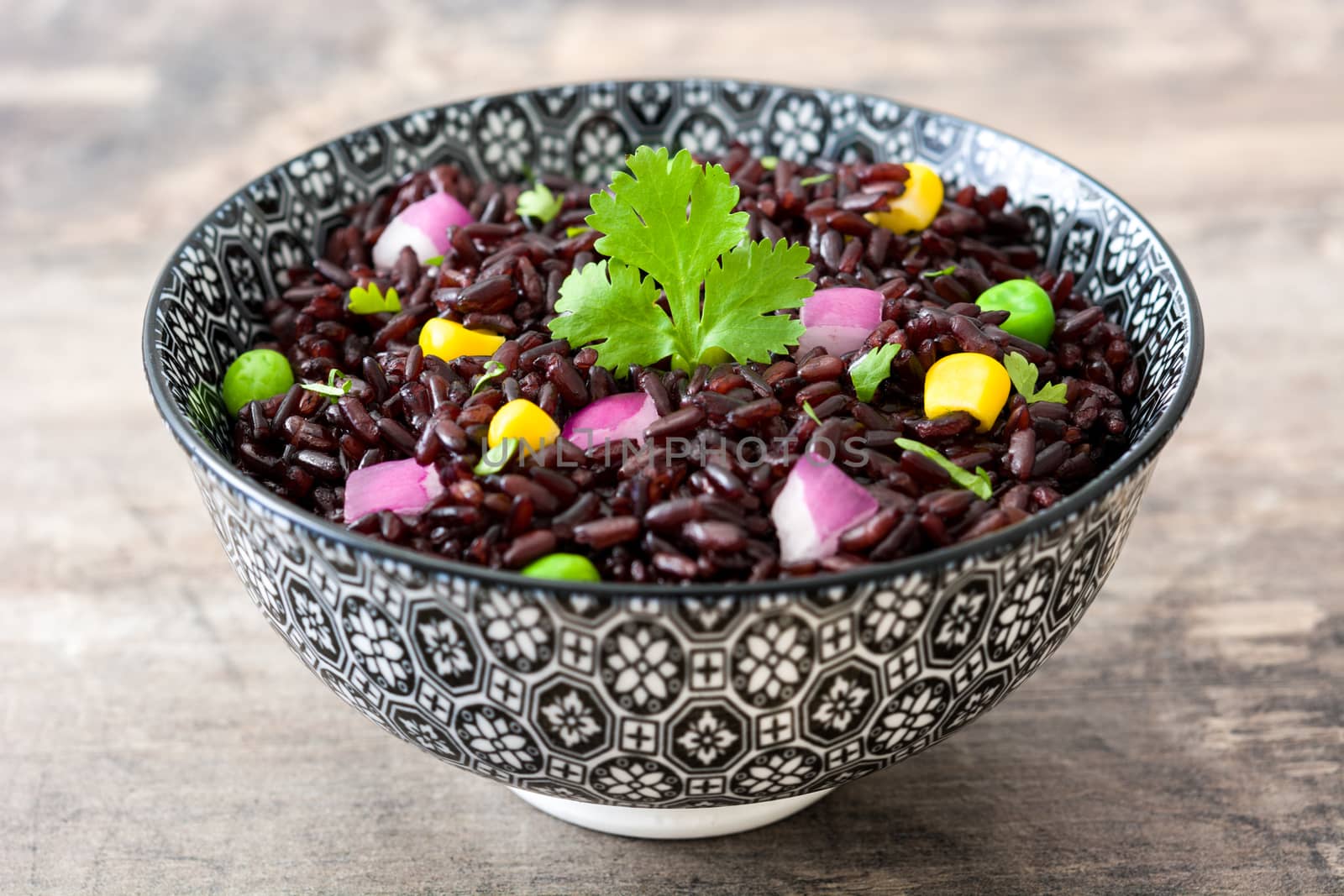 Black rice and vegetables on a wooden table by chandlervid85