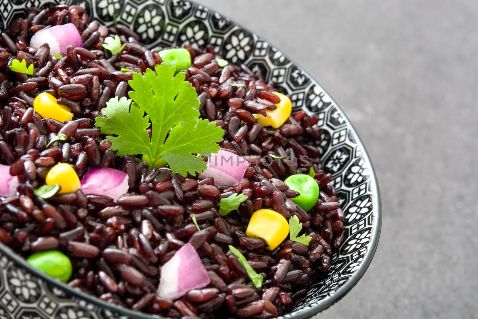 Black rice and vegetables in a bowl on black stone by chandlervid85