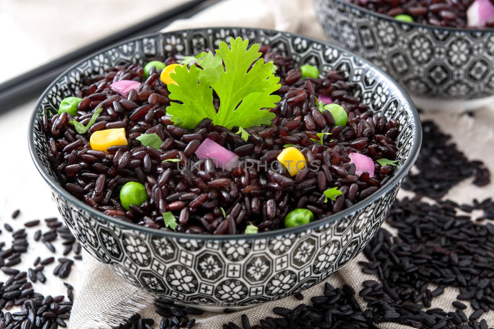 Black rice in a bowl and vegetables on wooden table by chandlervid85