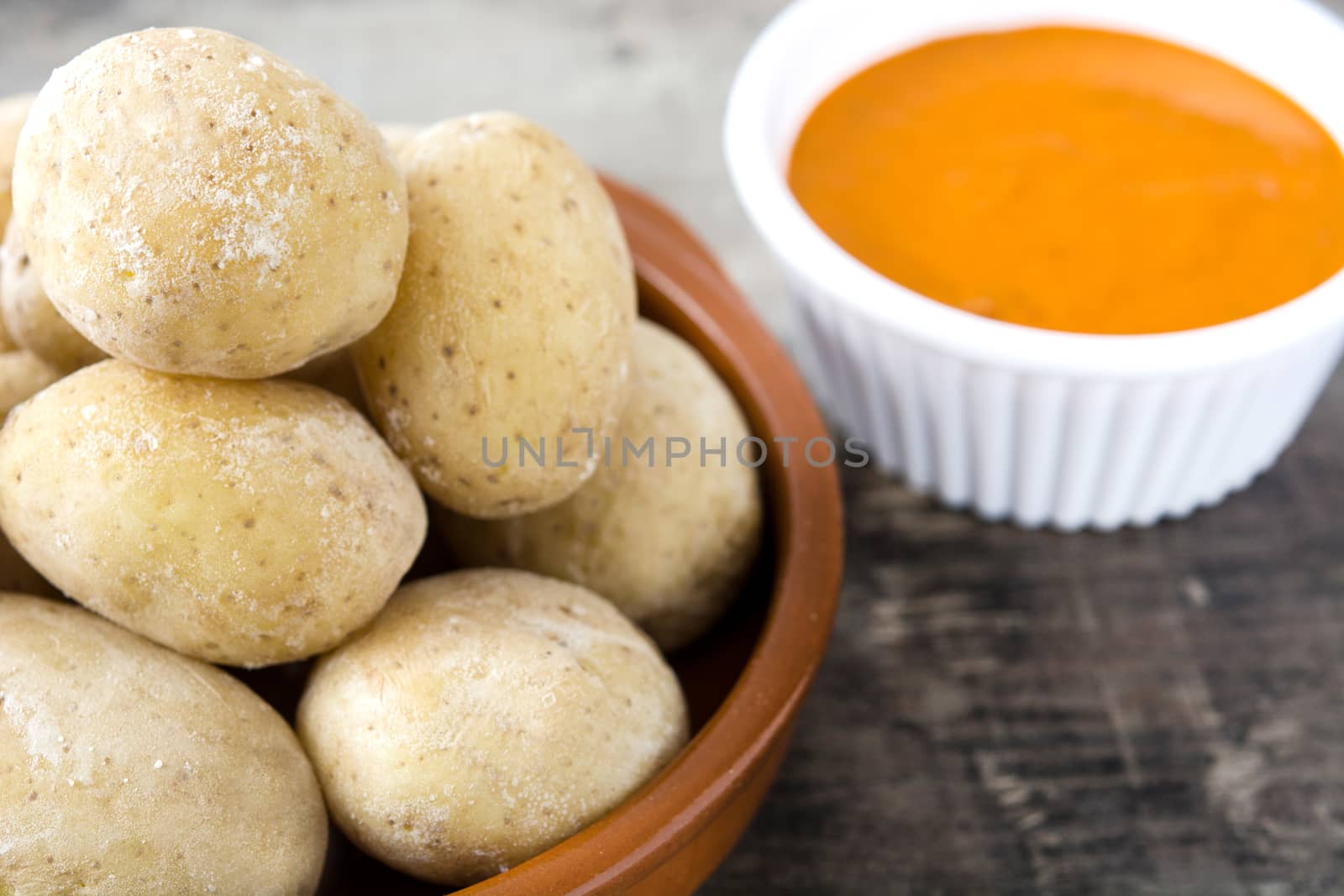 Canarian potatoes (papas arrugadas) with mojo sauce on wooden table by chandlervid85