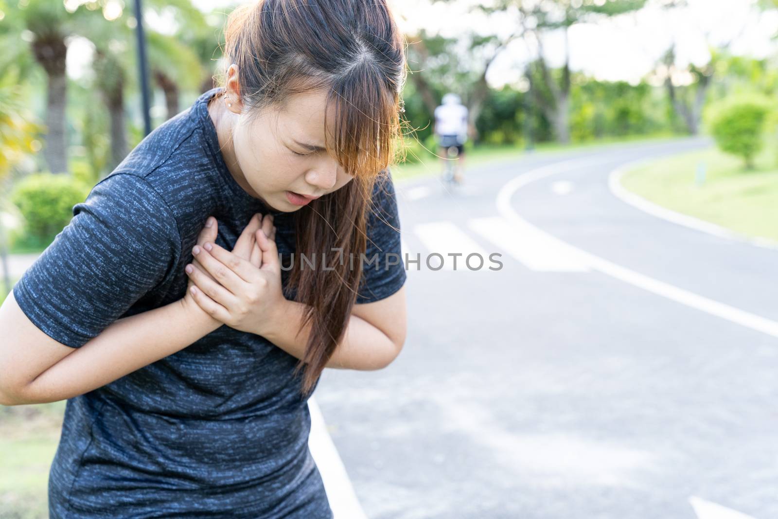 Exhausted female runner suffering painful angina pectoris or asthma breathing problems after training hard on summer. Running over training consequence. by mikesaran