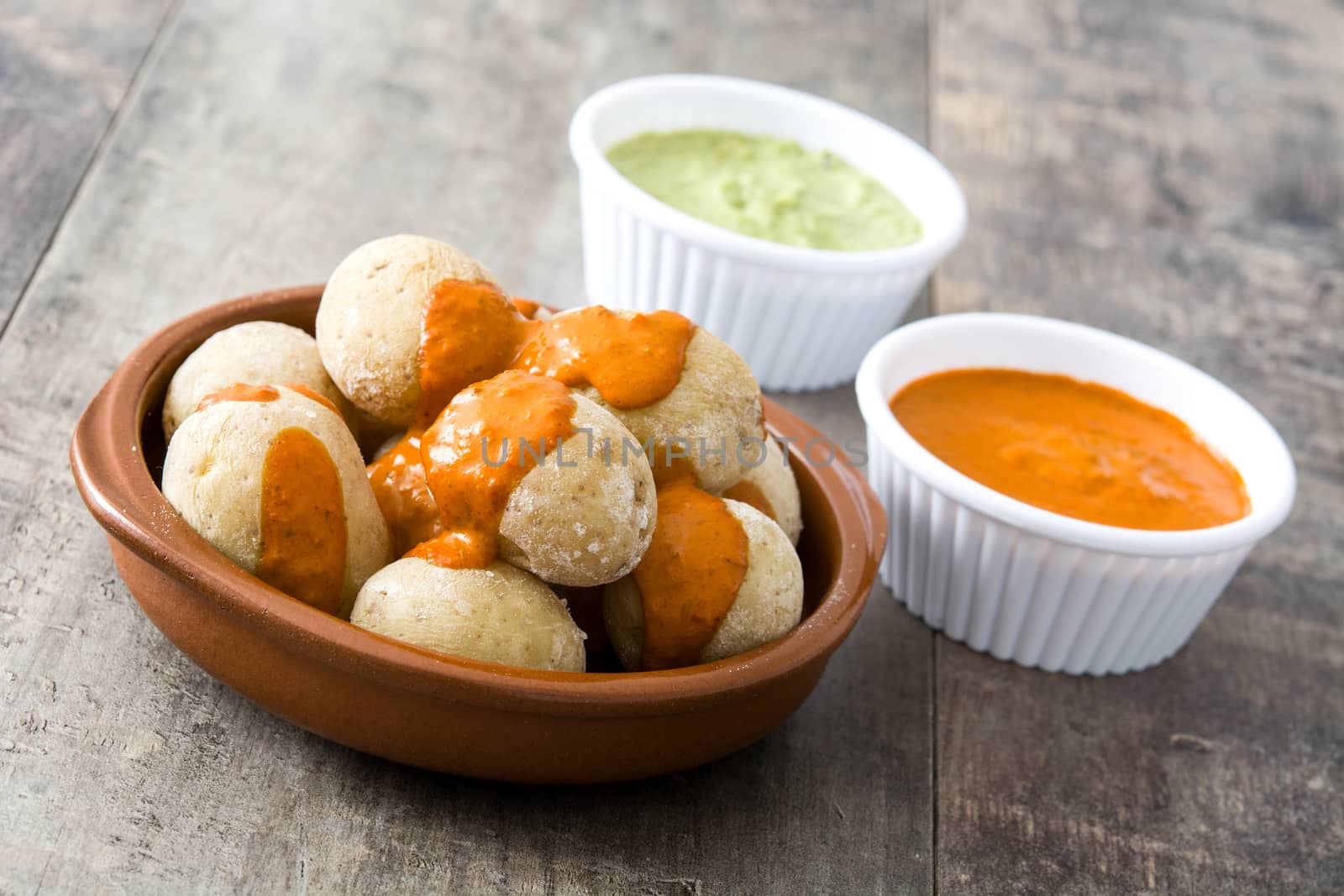 Canarian potatoes (papas arrugadas) with mojo sauce on wooden table by chandlervid85