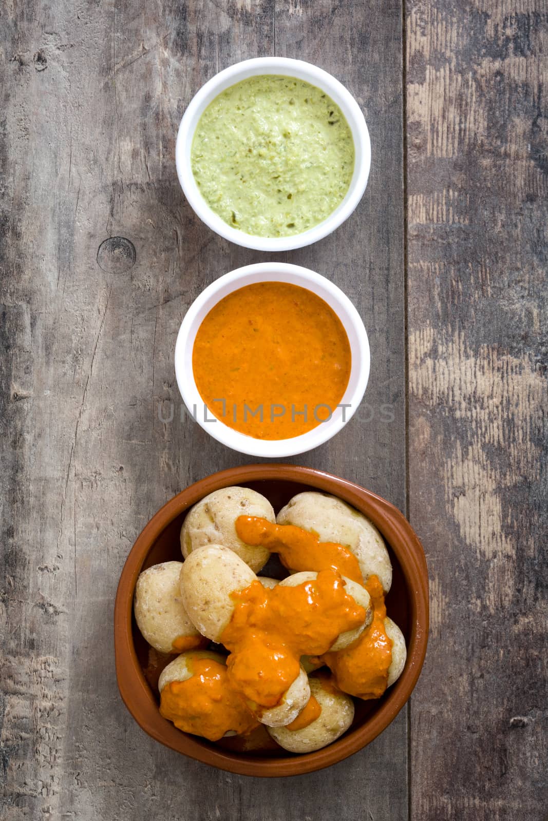 Canarian potatoes (papas arrugadas) with mojo sauce on wooden table by chandlervid85