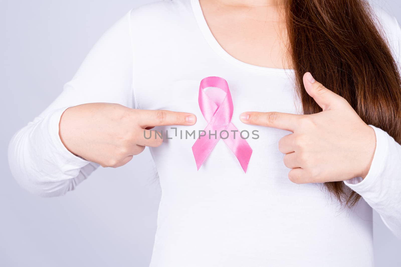 Breast cancer awareness ribbon on woman chest on grey background. Medical, healthcare for advertising concept.