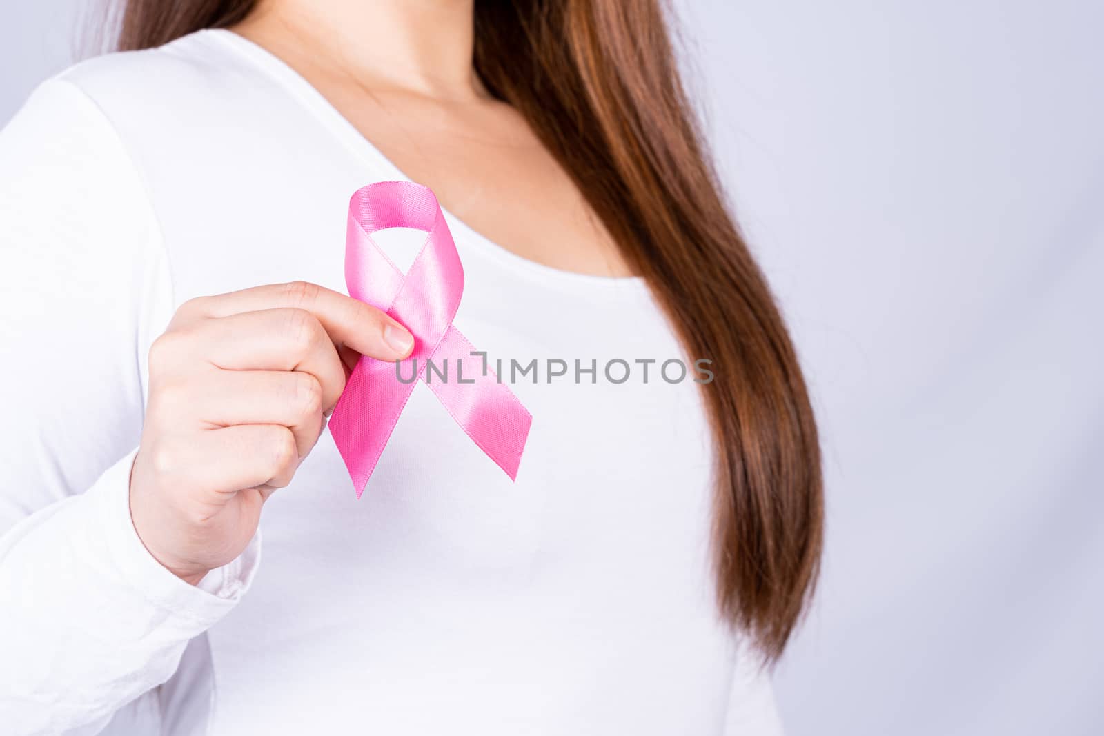 Breast cancer awareness ribbon on woman chest on grey background. Medical, healthcare for advertising concept.