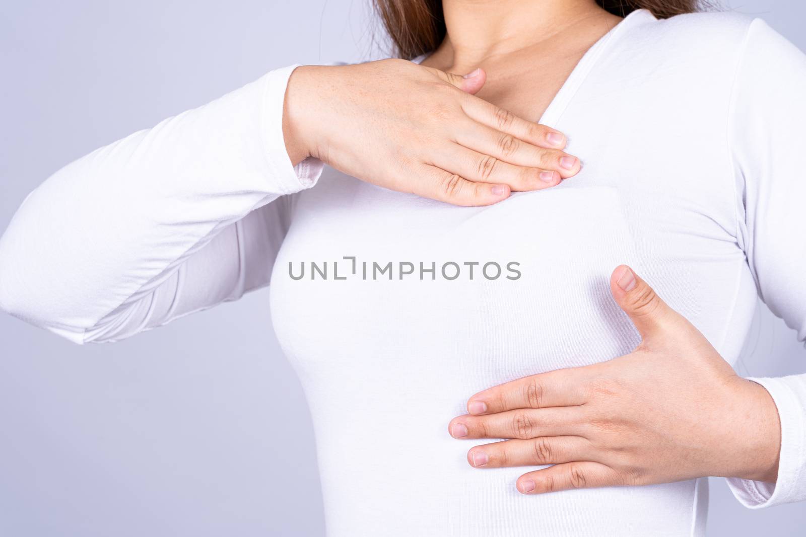 Woman hands doing breast self exam for checking lumps and signs of breast cancer on grey background. Medical, healthcare for advertising concept.