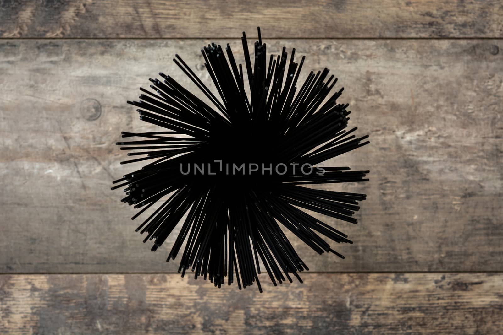 Raw black spaghetti with prawns, tomatoes and basil on wooden background