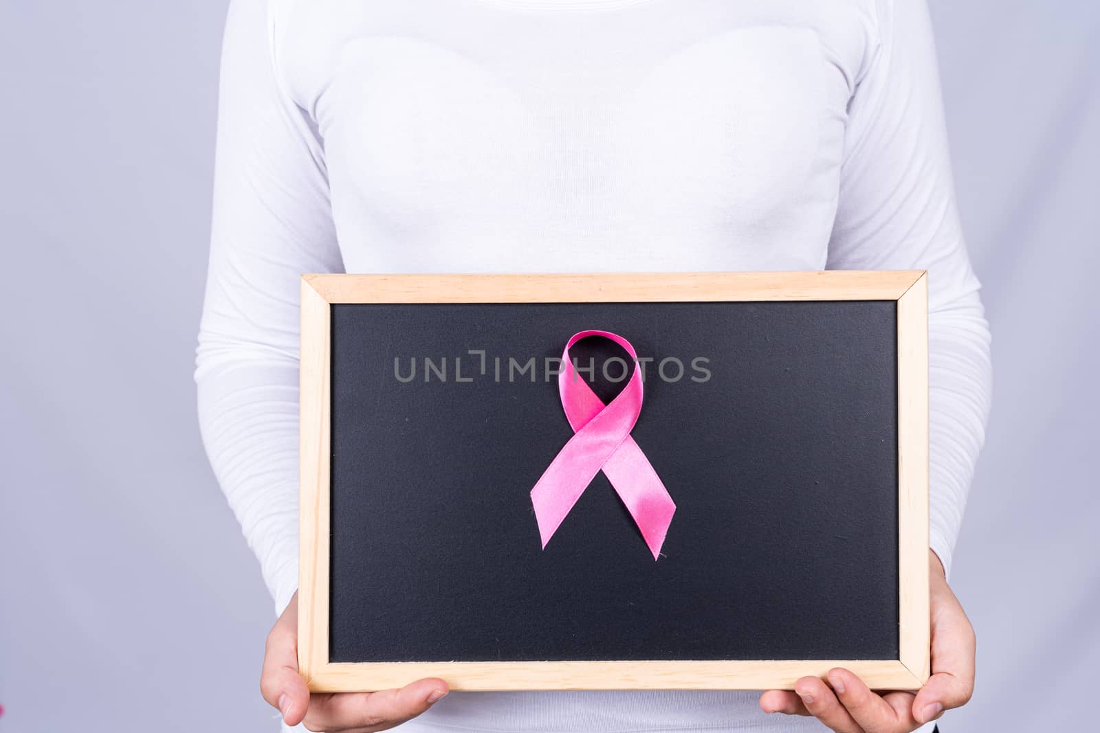 Breast cancer awareness ribbon on blackboard holding by woman. Medical, healthcare for advertising concept.