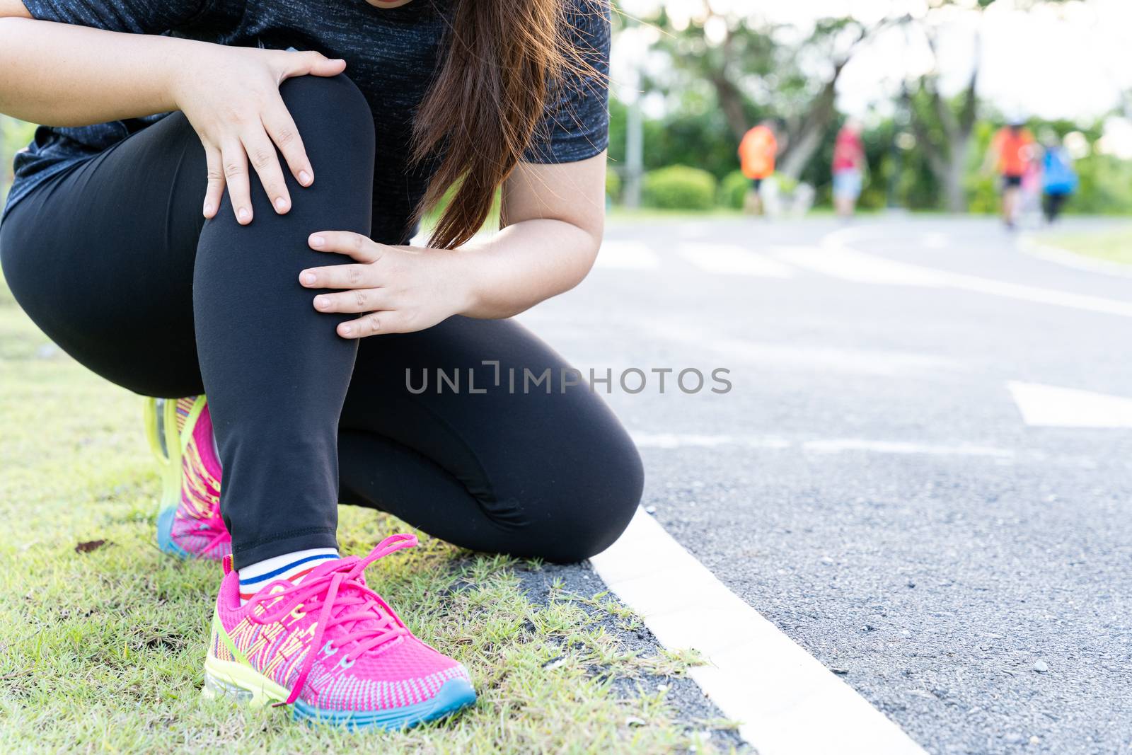 Asian woman use hands hold on her knee injury while running on road in the park, Injury from workout concept.