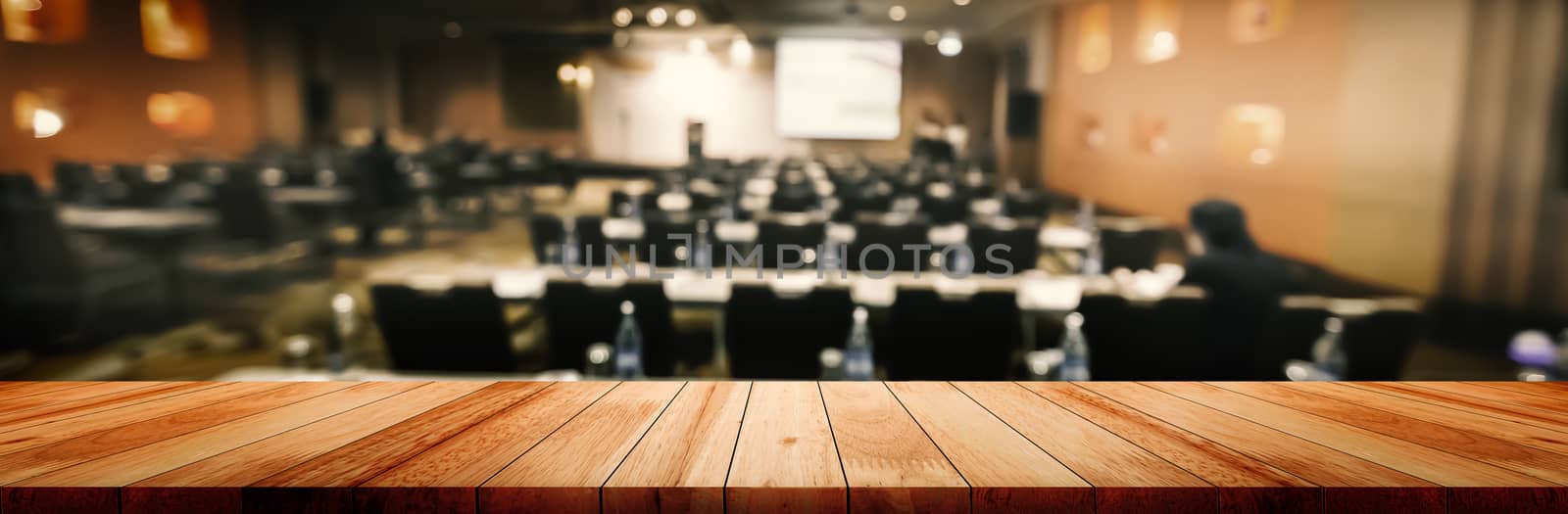 Panoramic empty clean wood counter table top on blur student study in classroom white light background for product education learning hall centre, Abstract Blurry wooden desk scene display or montage.
