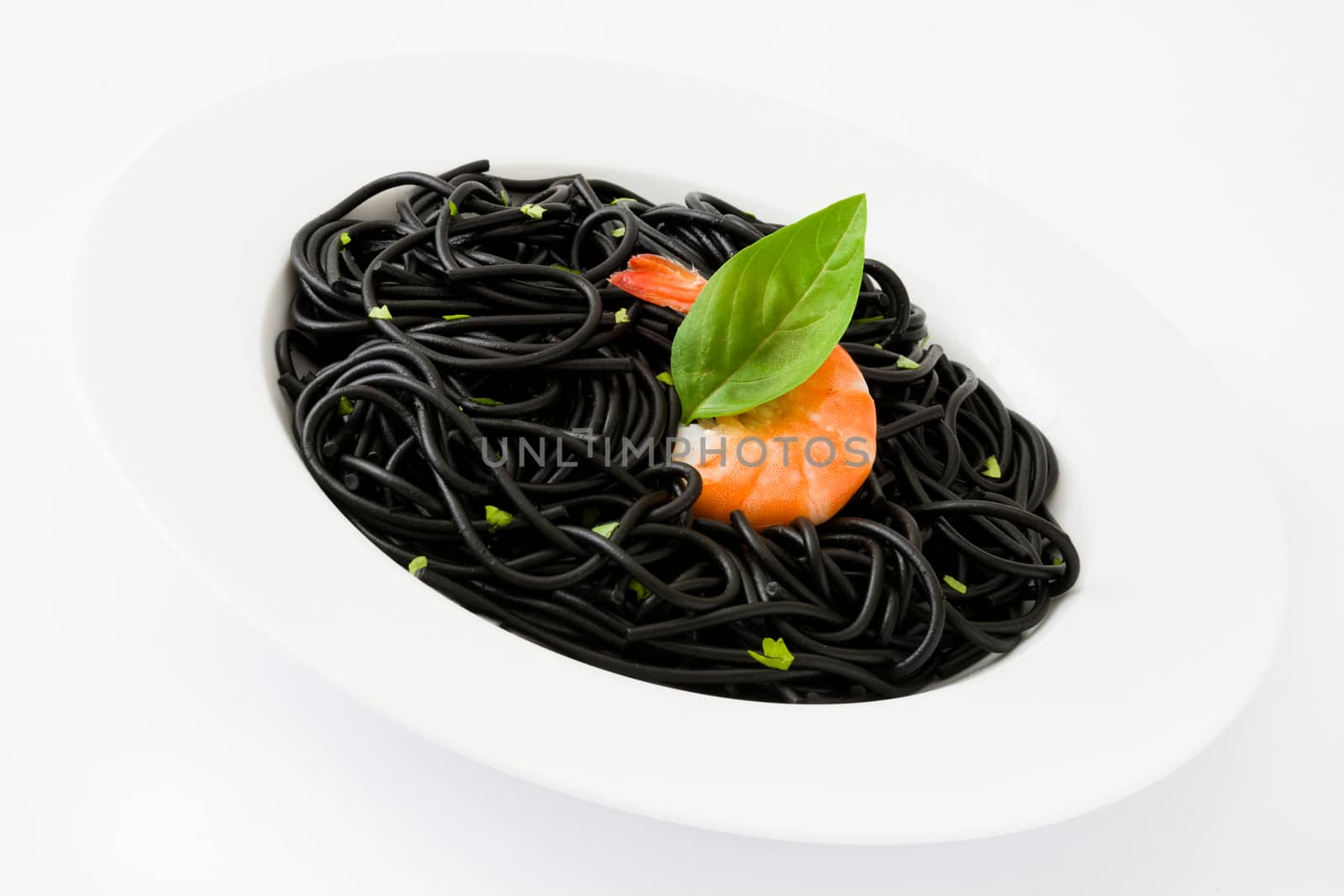 Black spaghetti with prawns and basil isolated on white background by chandlervid85