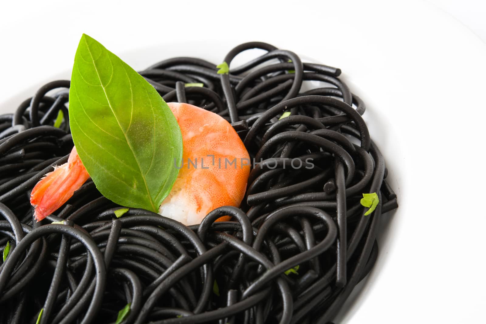Black spaghetti with prawns and basil isolated on white background by chandlervid85