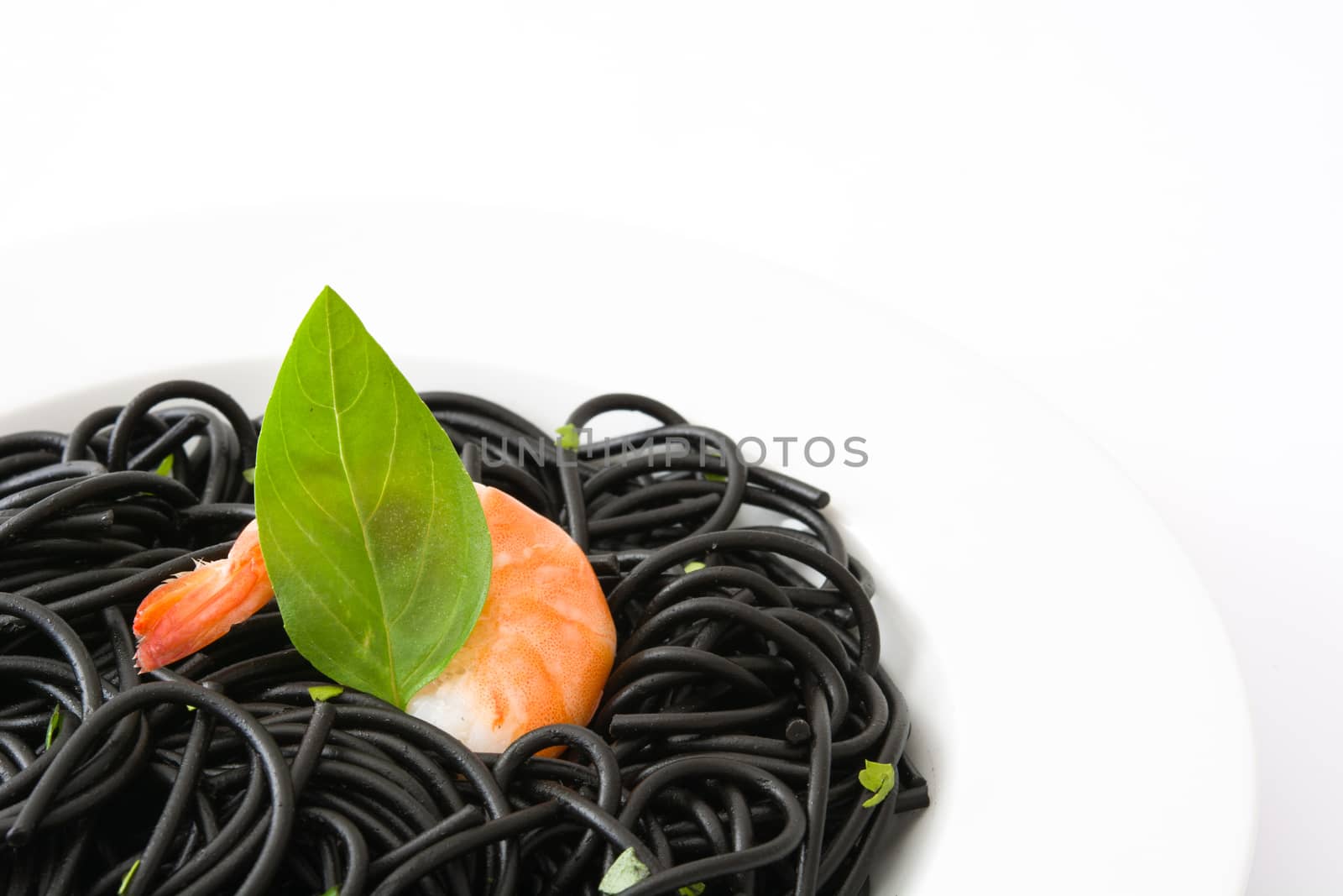 Black spaghetti with prawns and basil isolated on white background by chandlervid85