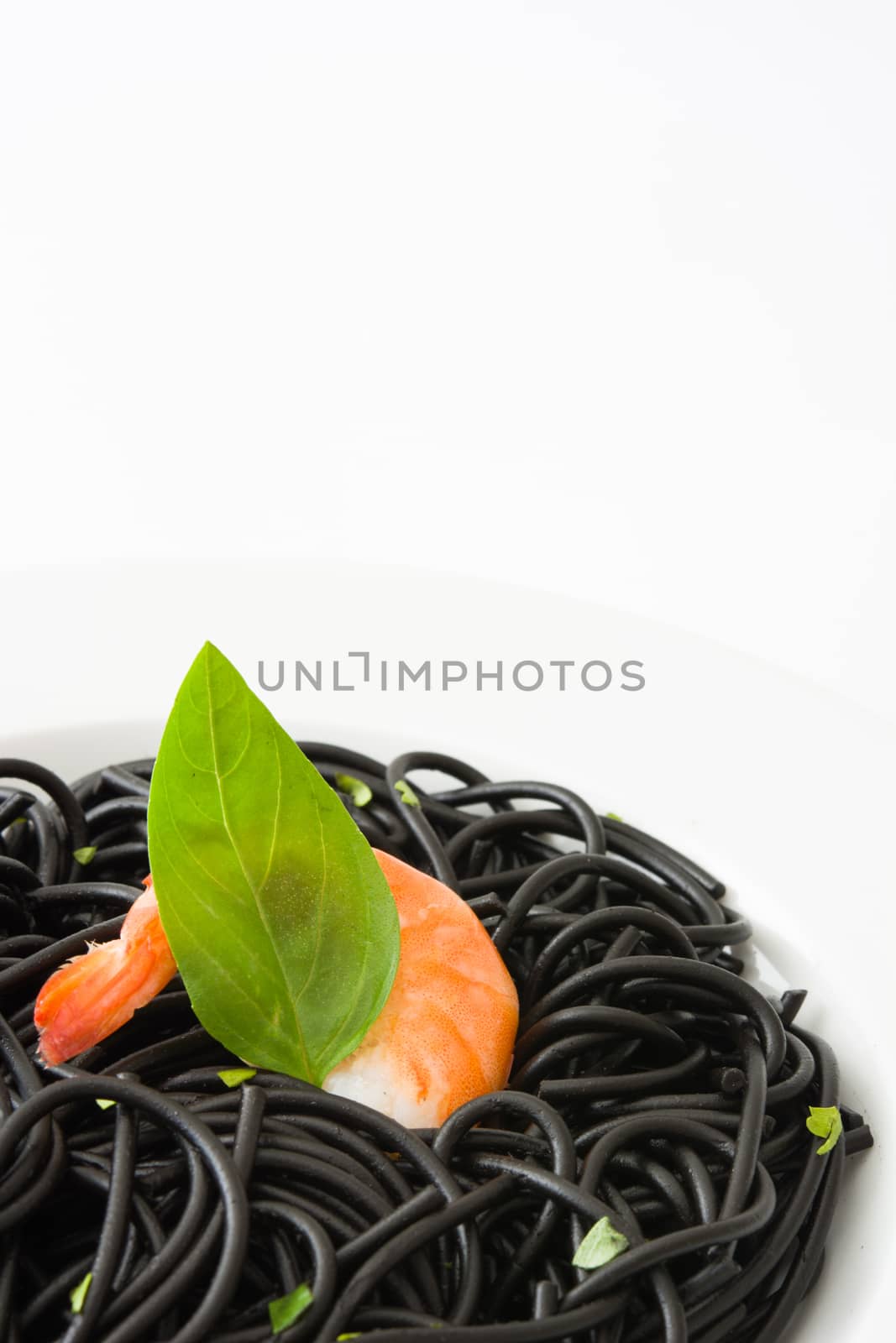 Black spaghetti with prawns and basil isolated on white background