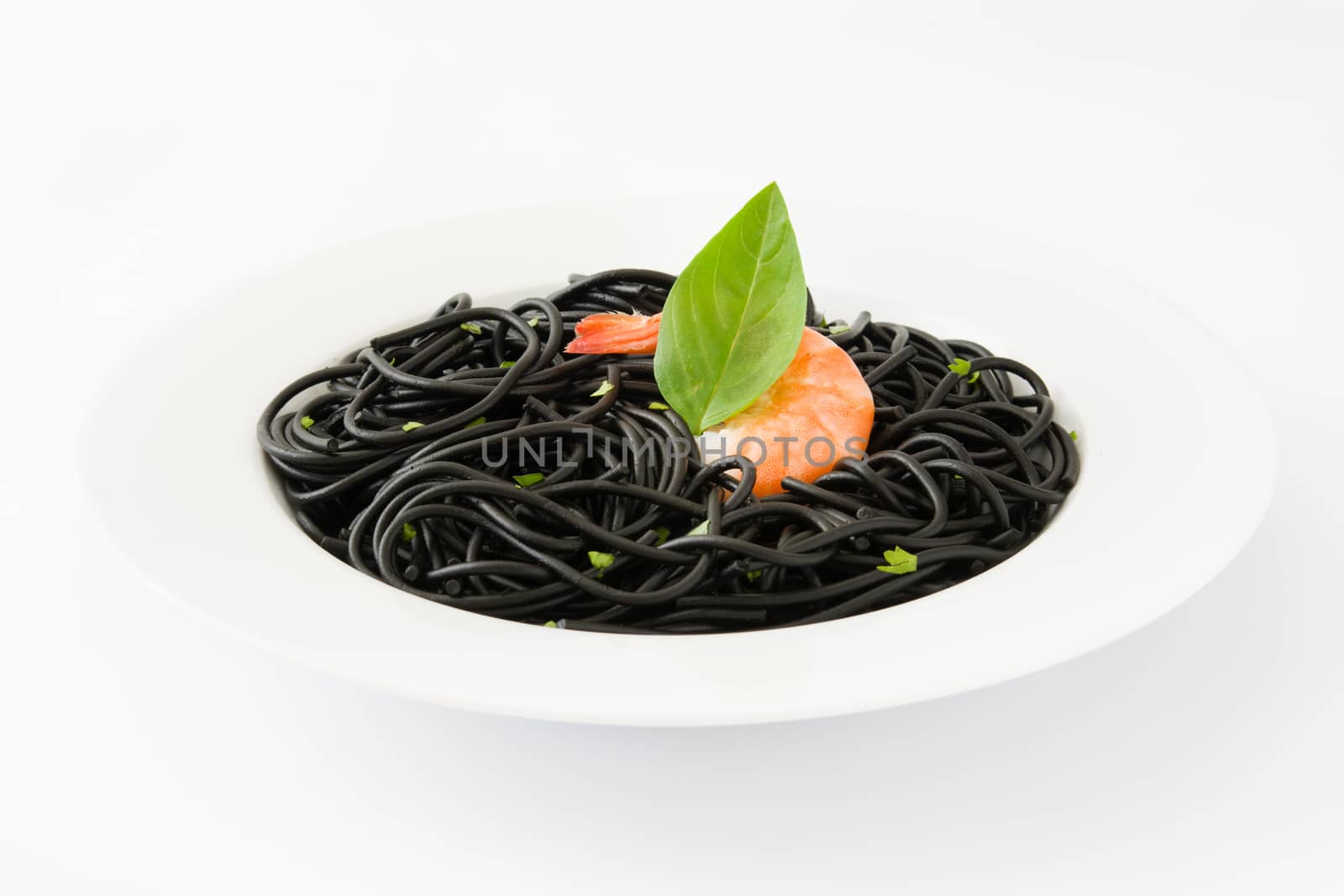 Black spaghetti with prawns and basil isolated on white background