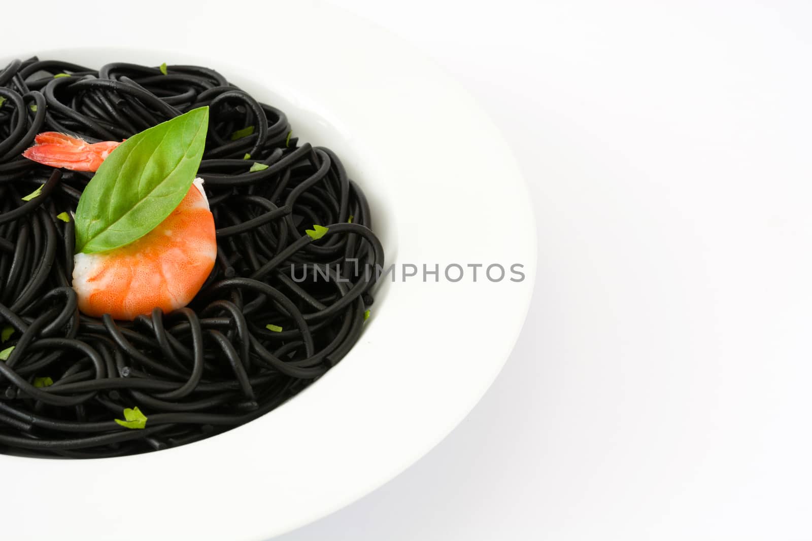 Black spaghetti with prawns and basil isolated on white background