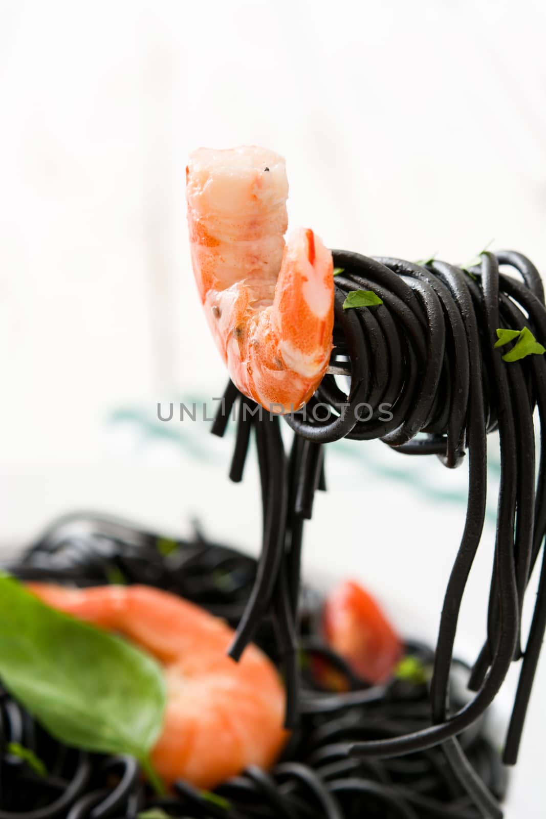 Black spaghetti with prawns on a fork by chandlervid85