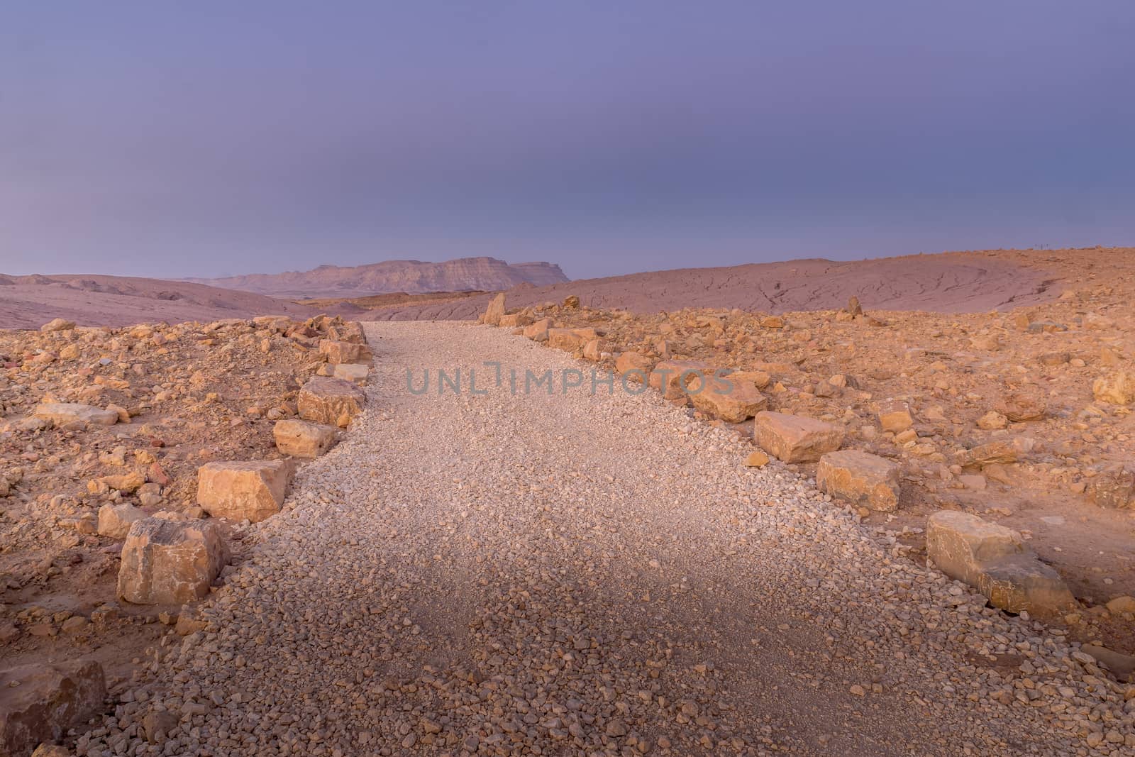 Blue hour view with a footpath and Mount Ardon, in Makhtesh (crater) Ramon, the Negev Desert, Southern Israel