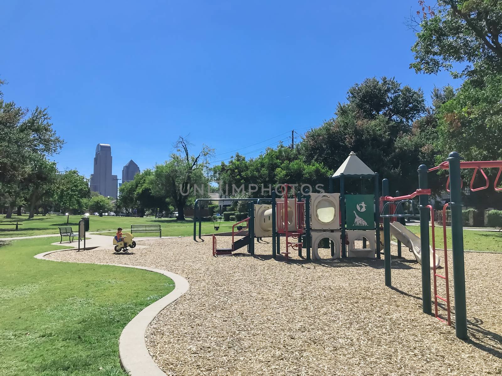Empty kid playground surrounded by large trees with skyscrapers background in downtown Dallas, Texas, USA by trongnguyen