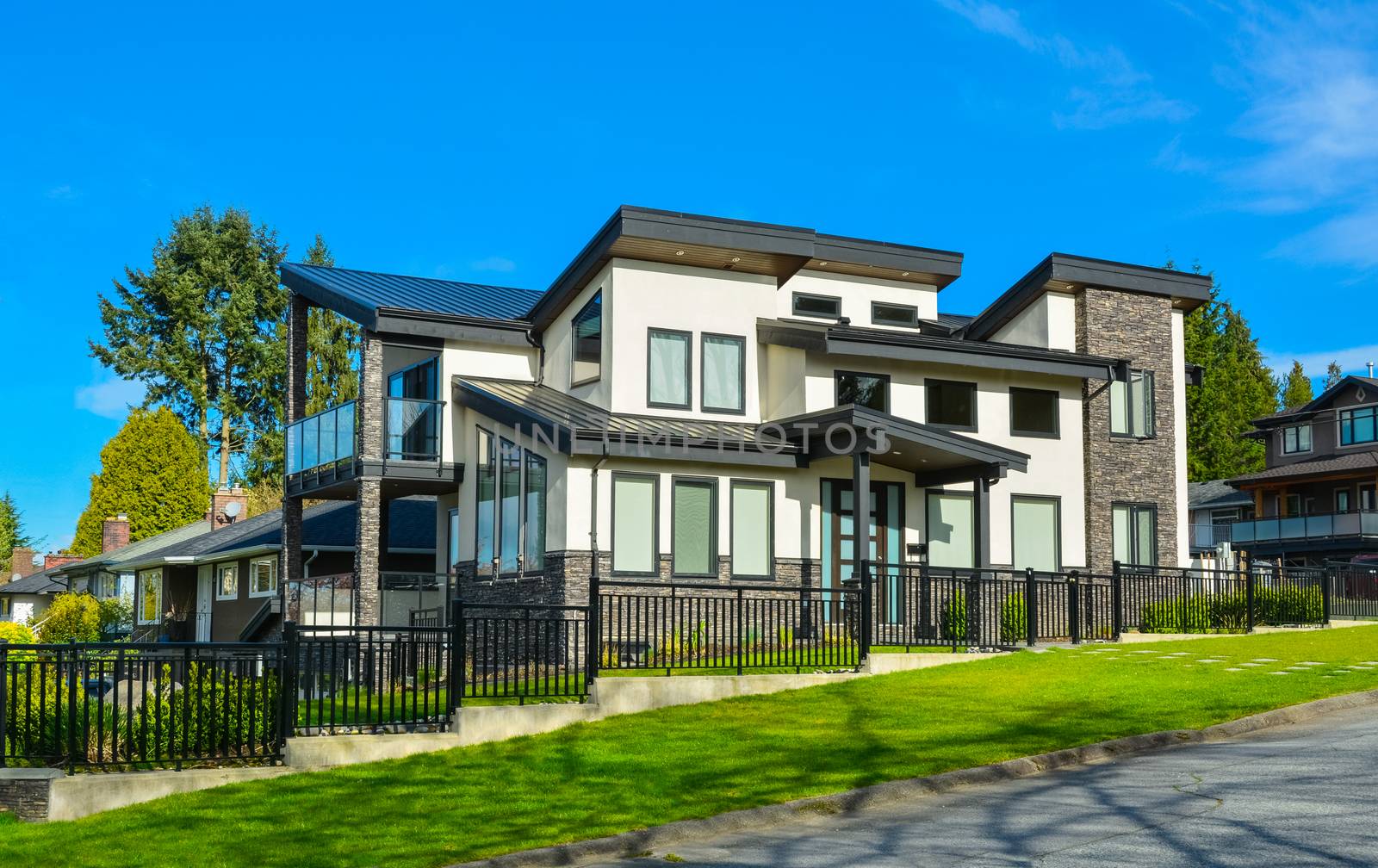 New residential house with concrete tile pathway over front lawn and metal fence in front