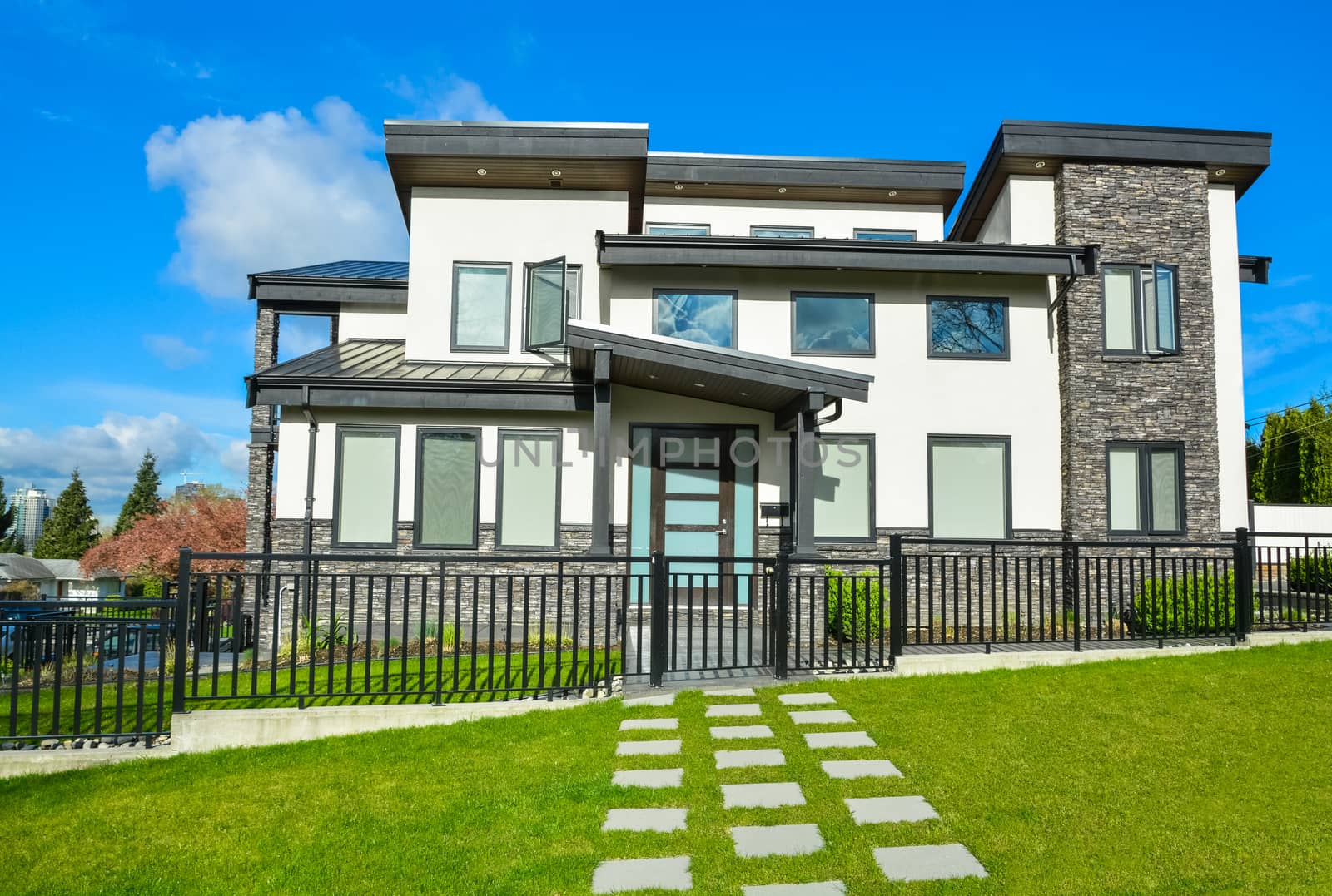 New residential house with concrete tile pathway over front yard lawn and metal fence in front