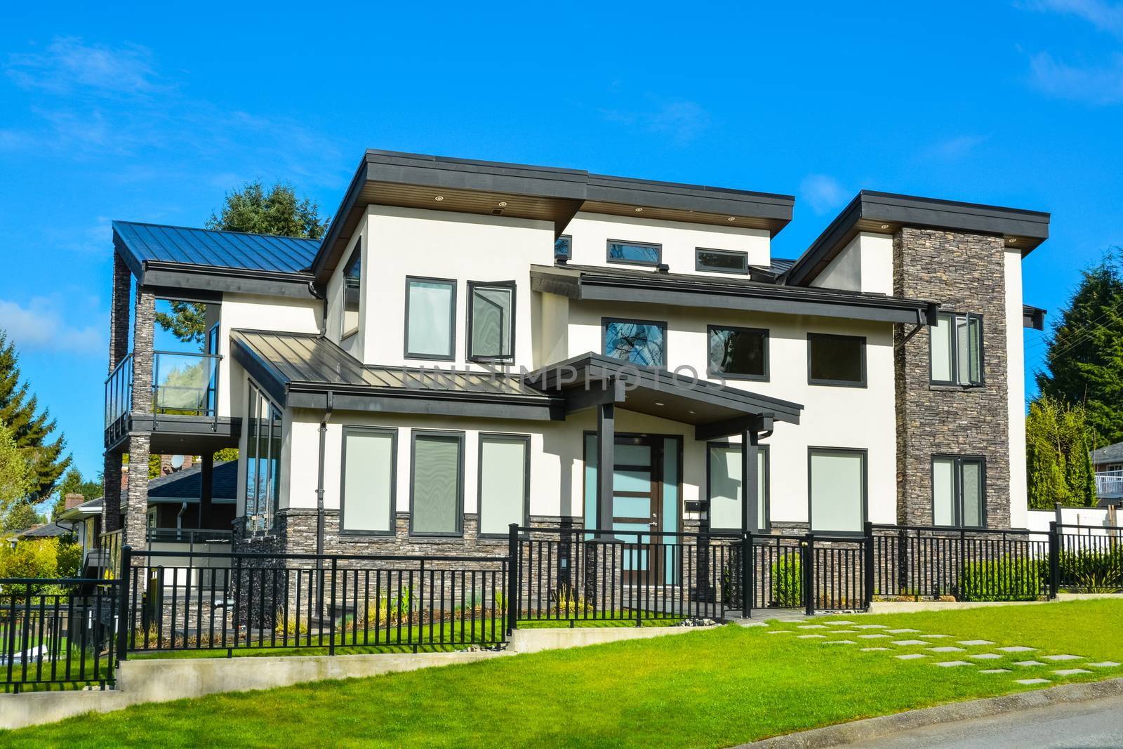 New residential house with concrete tile pathway over front lawn and metal fence in front