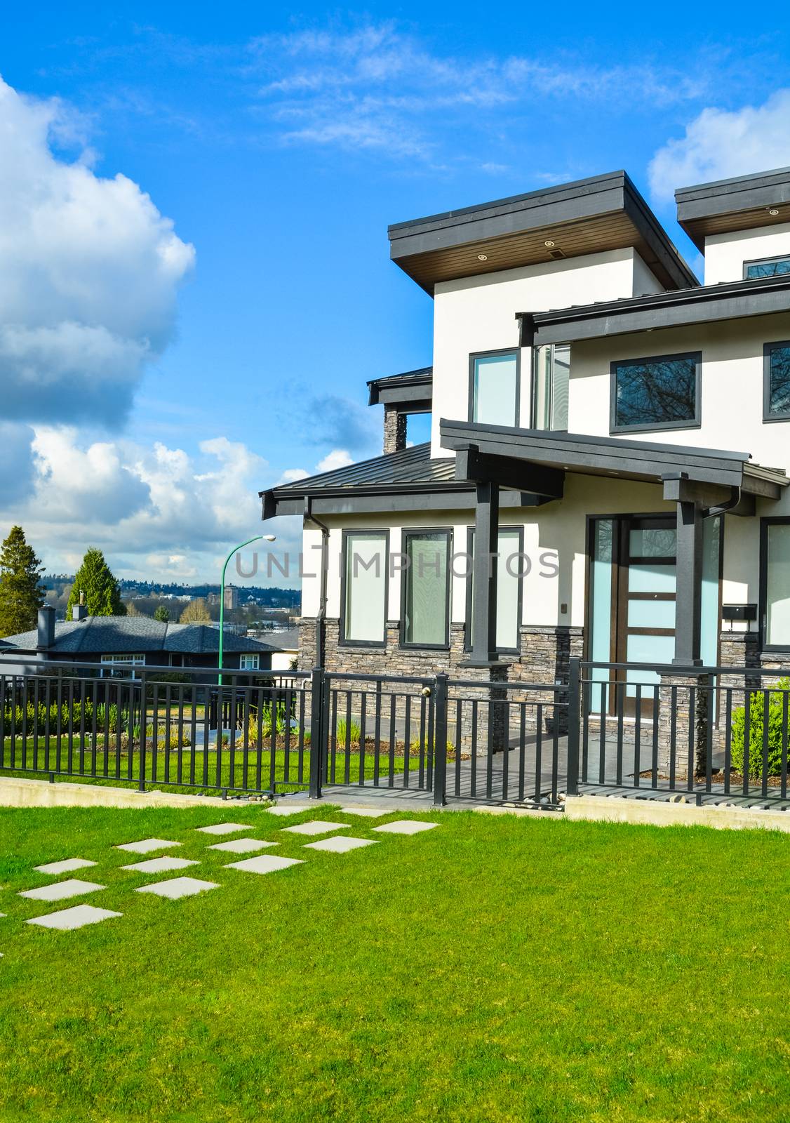New residential house with concrete tile pathway over front lawn and metal fence in front