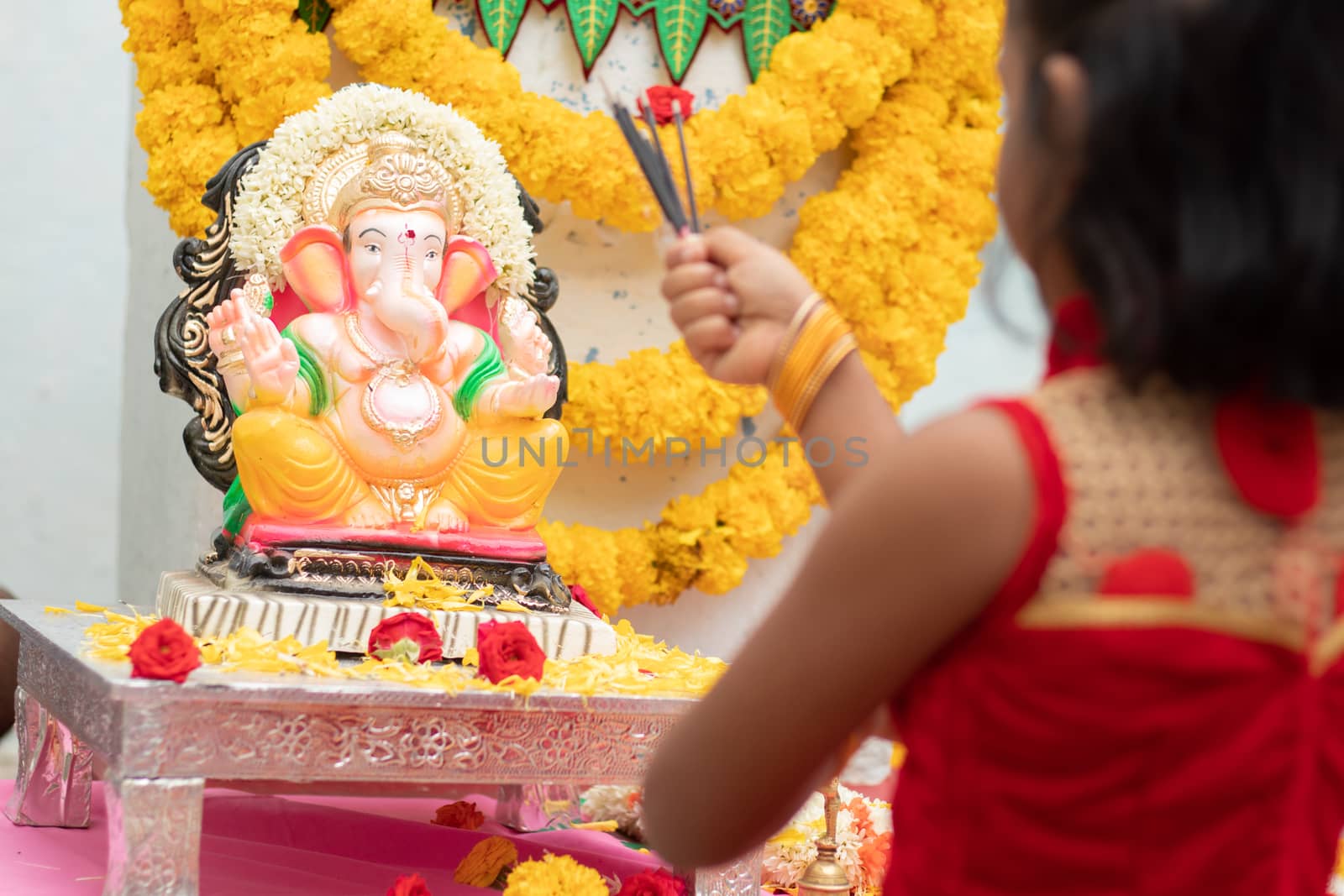 kid praying by closing eyes infront of god Ganesha idol by holding or offering incense in hand during ganapati festival celebration at home. by lakshmiprasad.maski@gmai.com