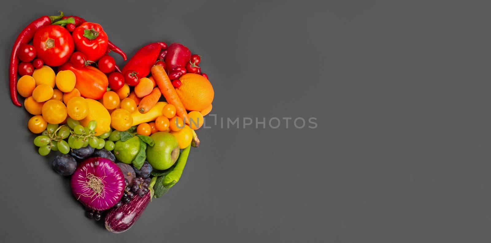 Rainbow heart of fruits and vegetables on gray background go vegetarian love healthy eating concept copy space for text