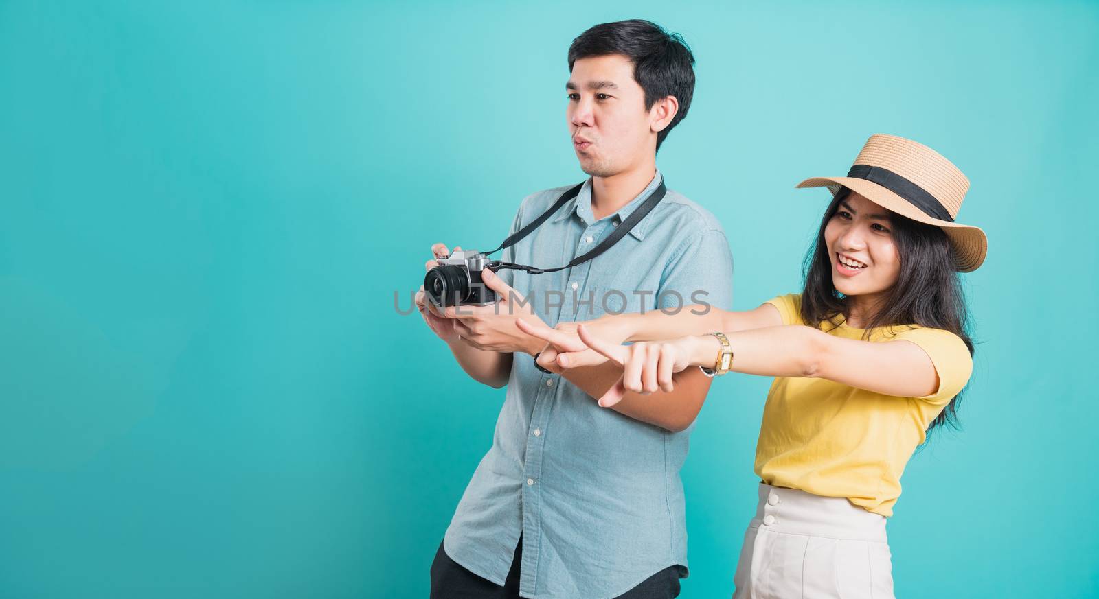 Happy Asian excited couple young beautiful woman point finger and handsome man holding camera shot photography in summer holiday travel tourists isolated on blue background with copy space for text