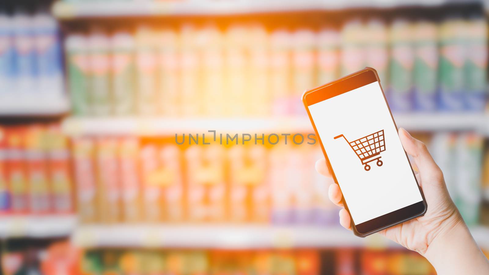 Shopping online concept. Hand holding black smartphone and white blank screen in blurry at shopping or department store background. Mock up shopping.