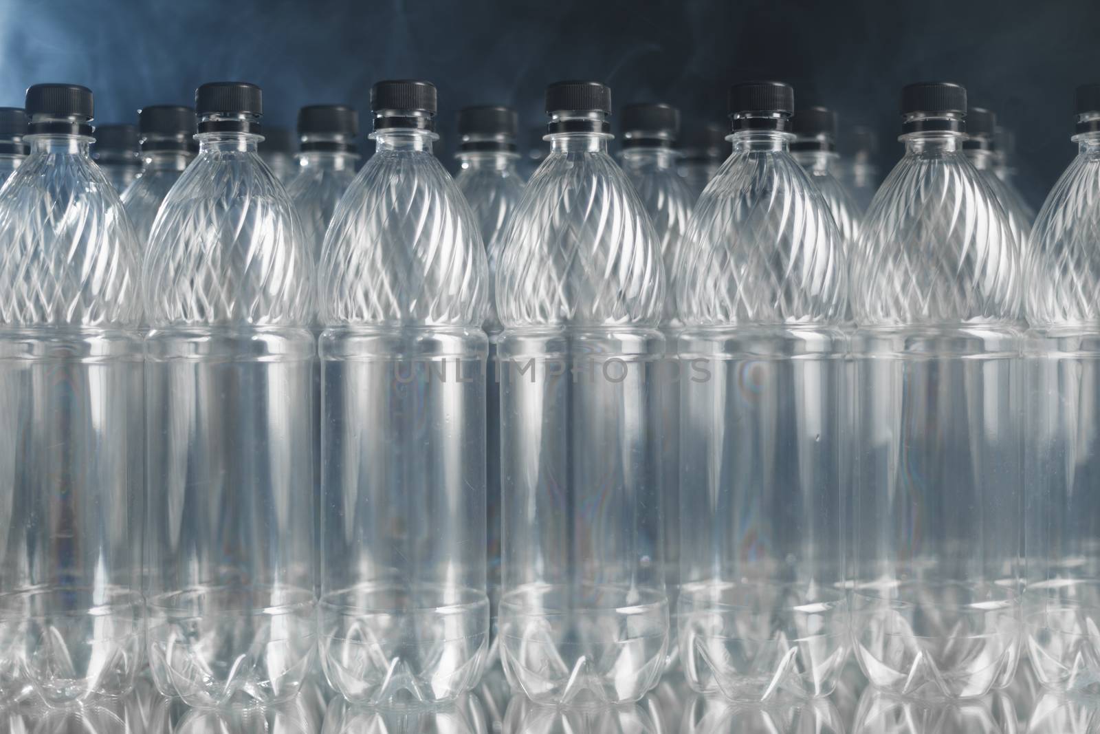 empty plastic bottles on black background with smoke, pollution concept by nikkytok