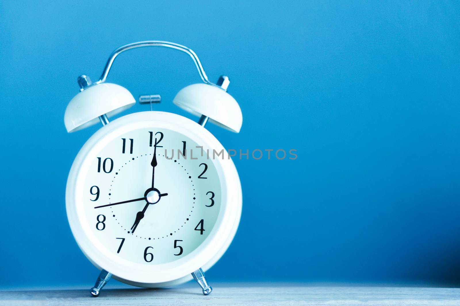 Alarm clock on blue table with soft light in the morning, selective