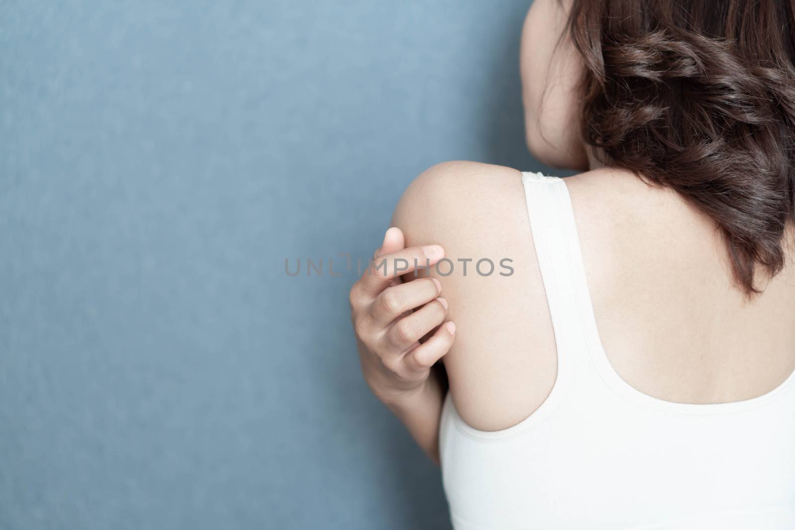 Closeup woman hand holding shoulder with pain on grey background by pt.pongsak@gmail.com