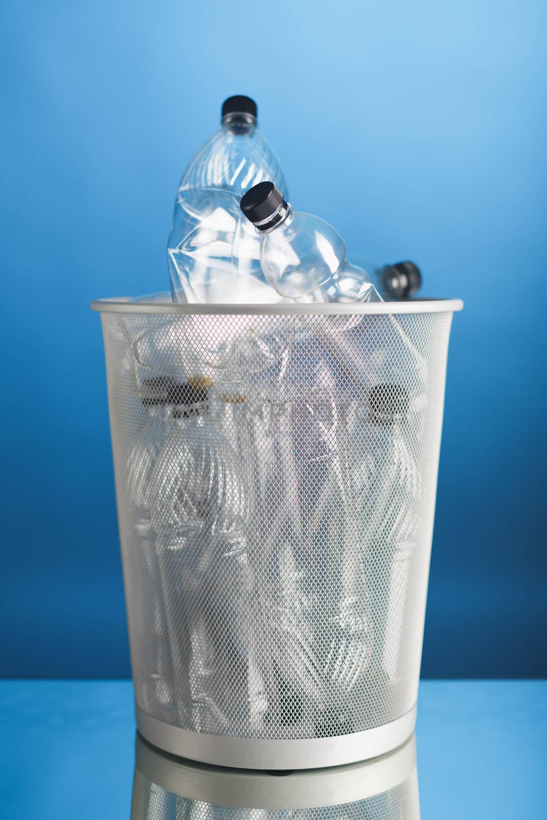 trash can with wasted plastic bottles, blue background