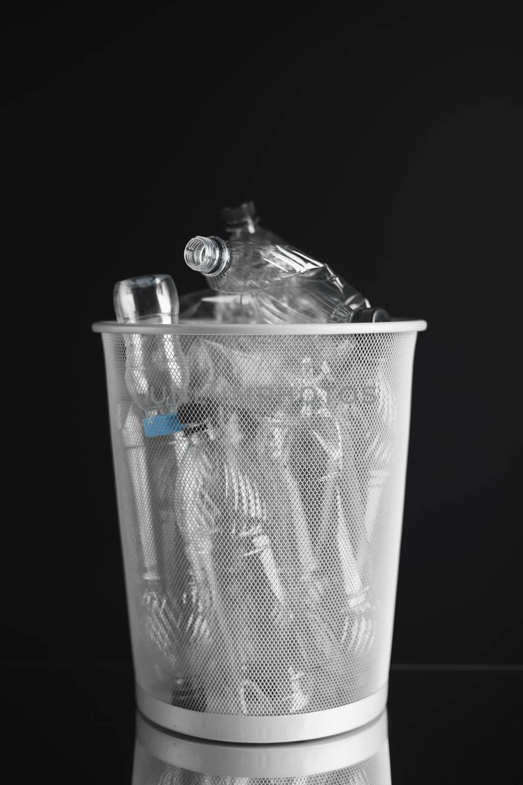 trash can with wasted plastic bottles, black background